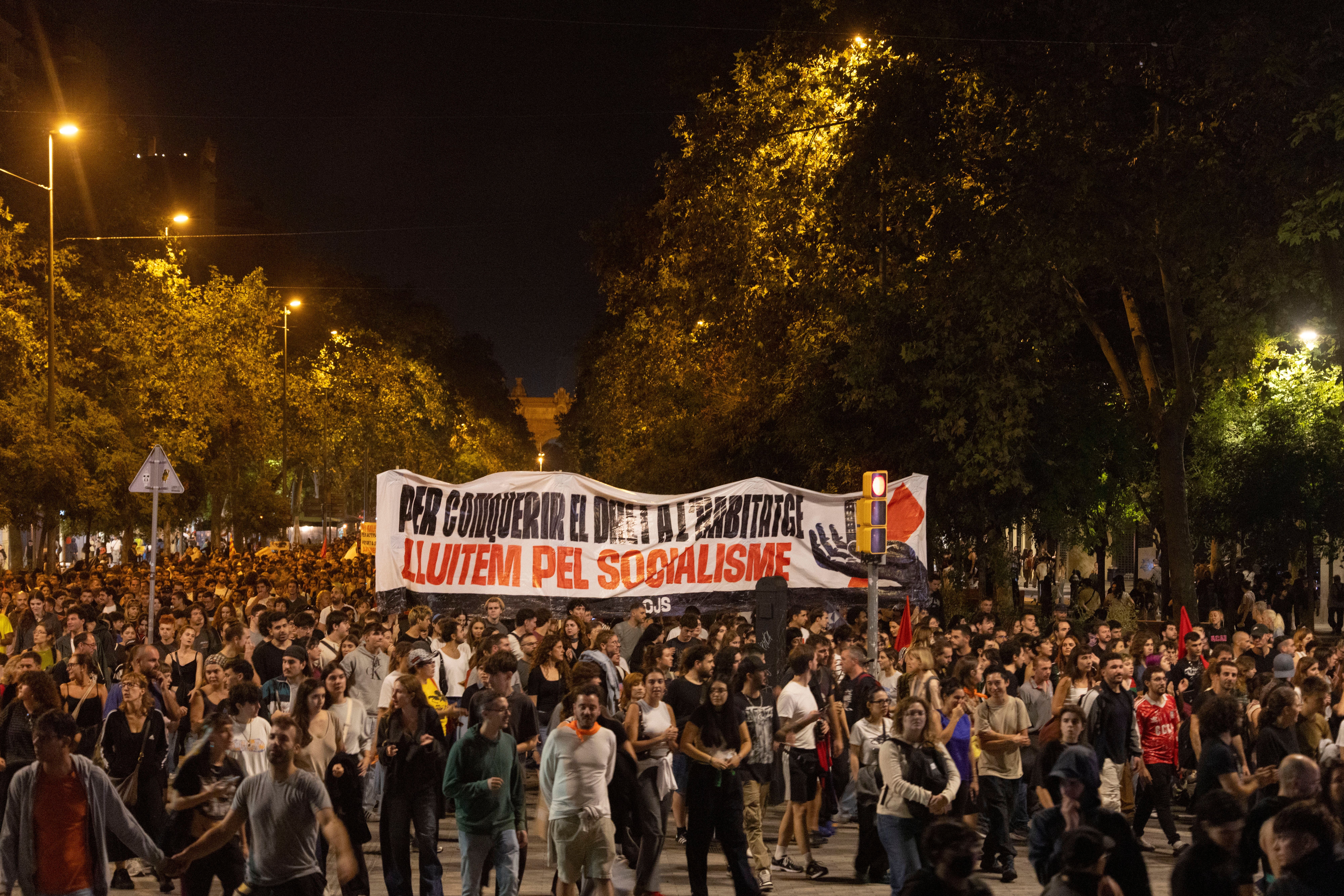 Große Menschenmenge protestiert nachts in Barcelona mit Banner für das Recht auf Wohnen.