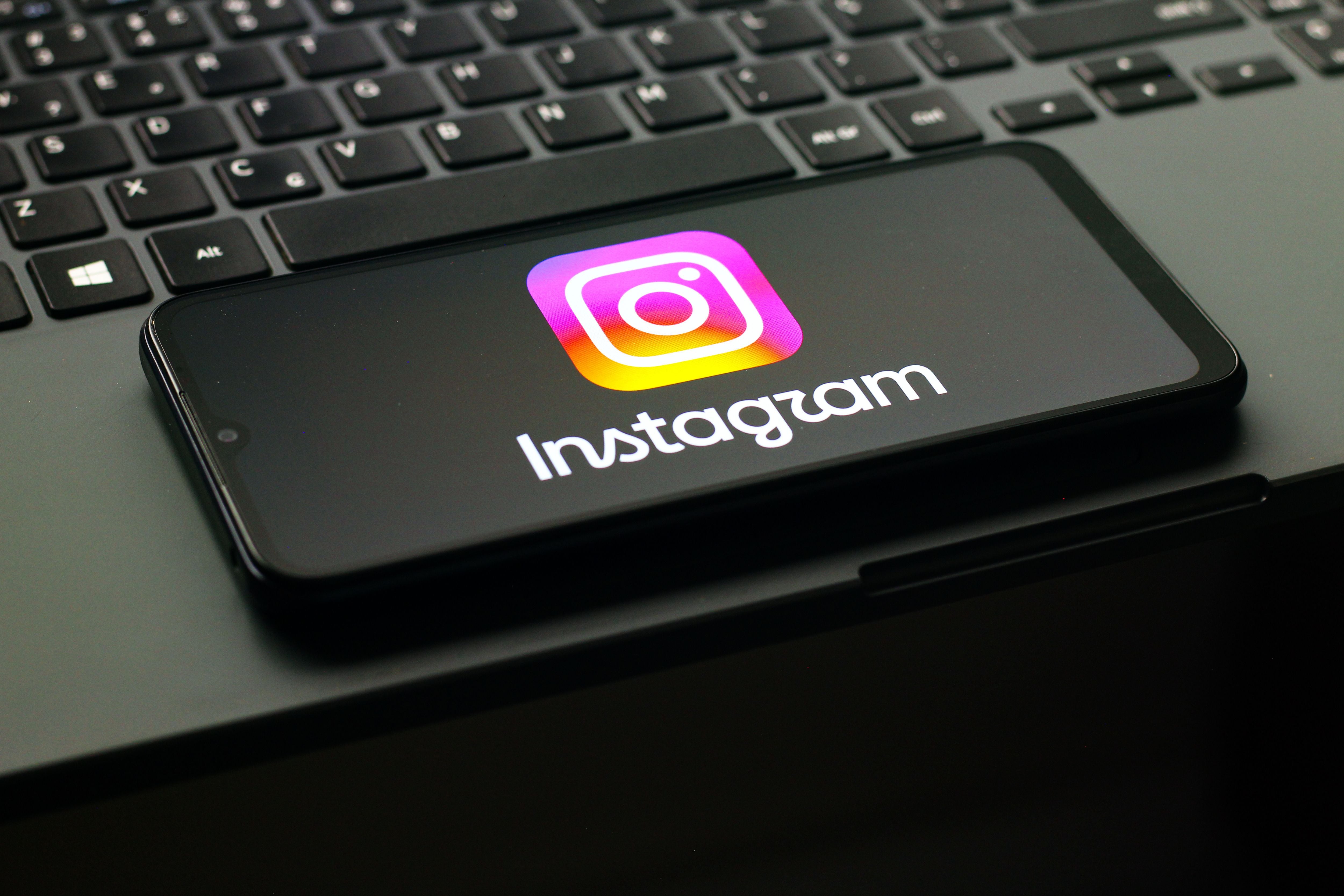 Ein Smartphone mit Instagram-Logo liegt auf einer Laptop-Tastatur.