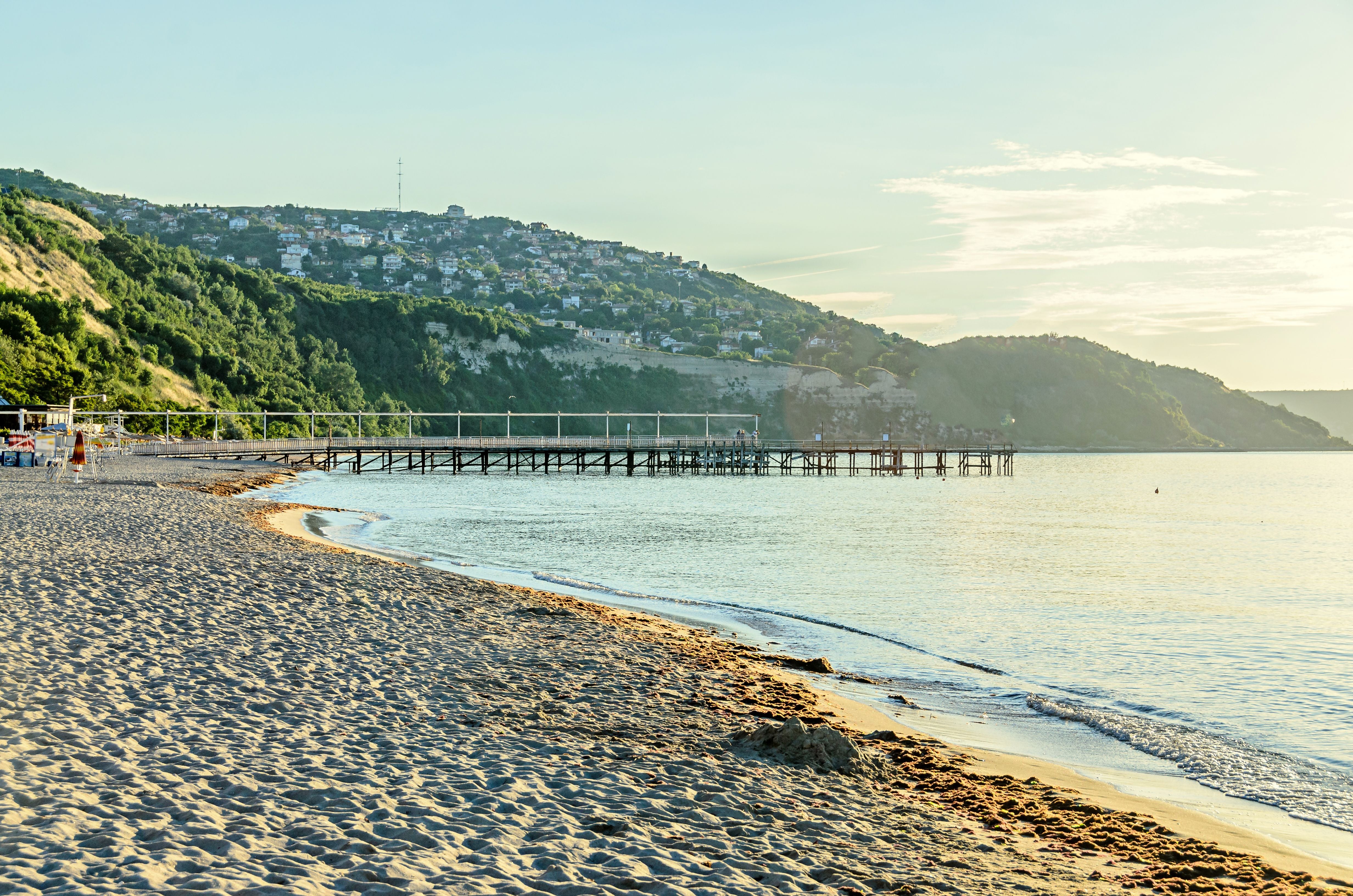 Sandstrand mit Steg am Schwarzen Meer bei Albena, Bulgarien, grüne Hügel im Hintergrund.