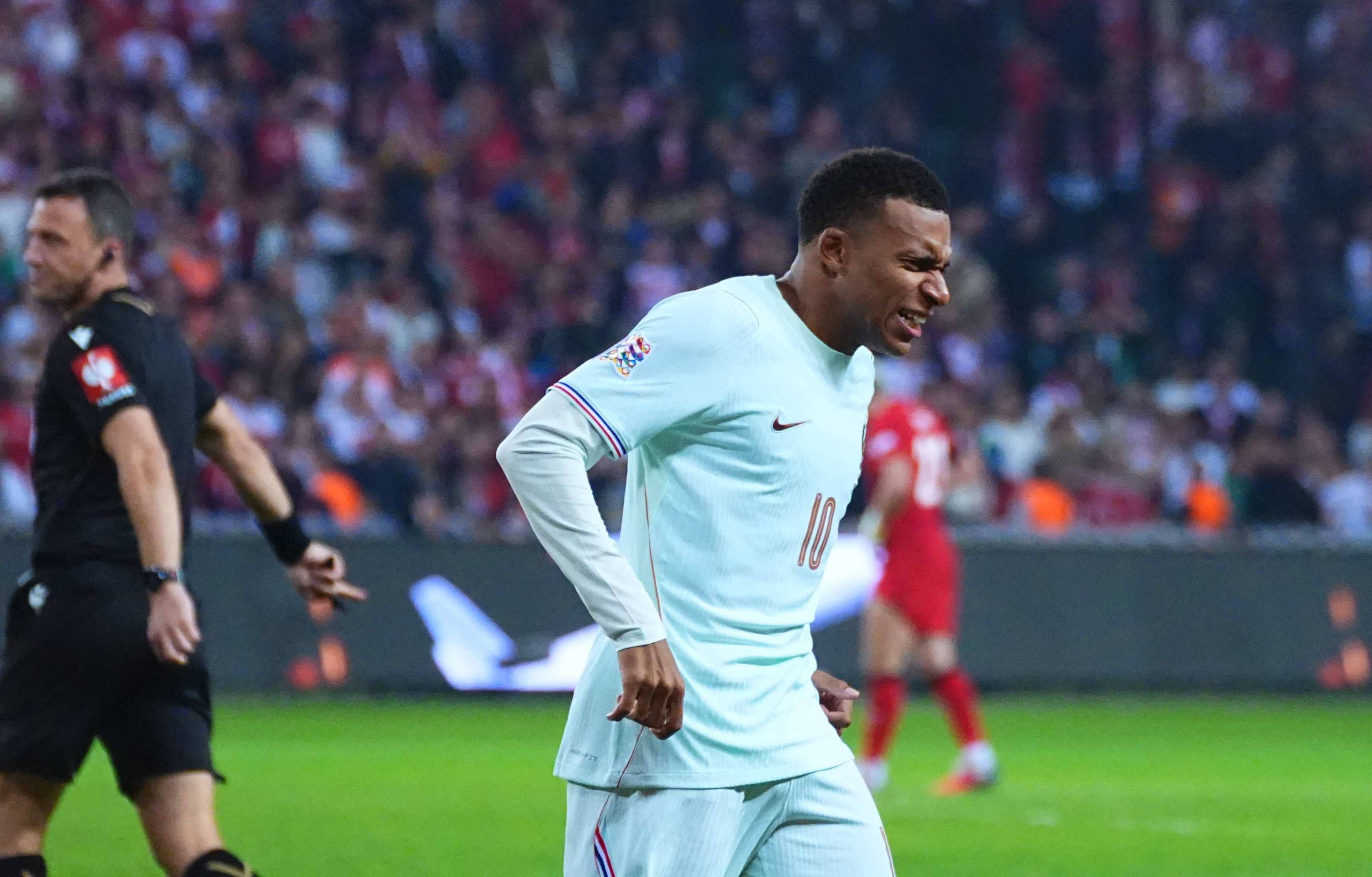 Kylian Mbappé im weißen Trikot während eines Fußballspiels, sichtbar angespannt.