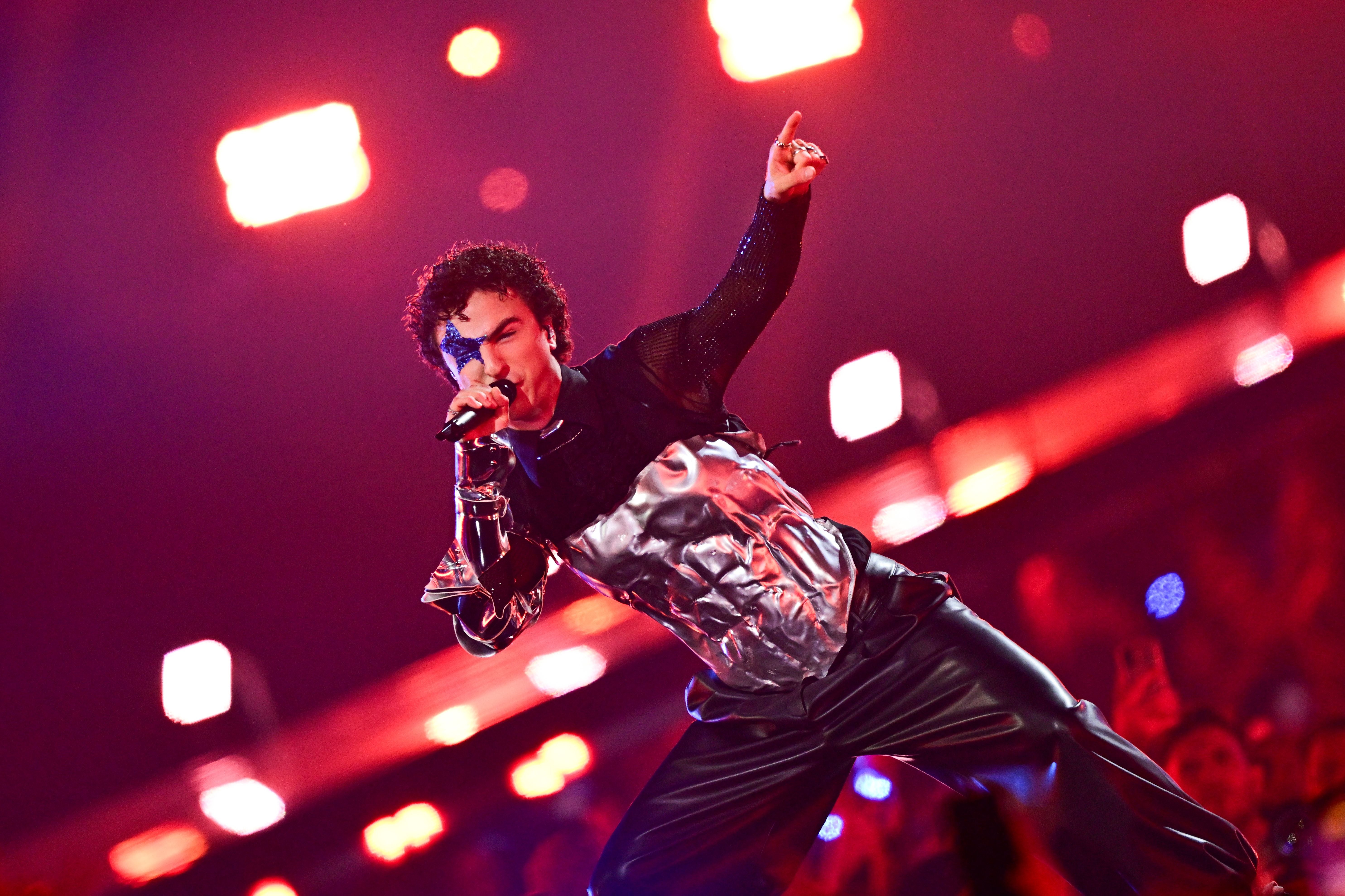 Sänger in futuristischem Outfit singt auf einer beleuchteten Bühne beim Eurovision Song Contest.
