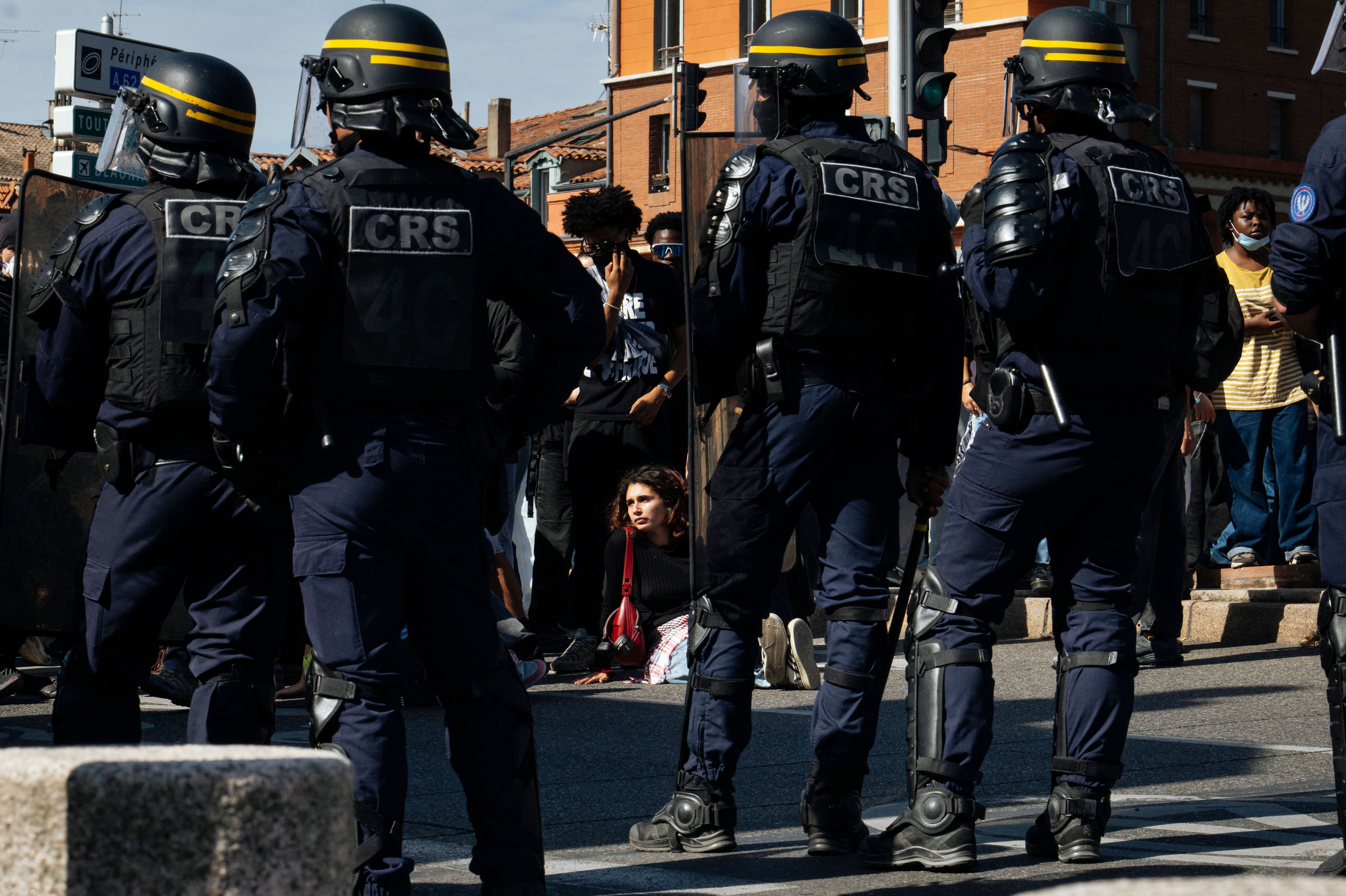 Mehrere CRS-Beamte stehen vor einer sitzenden Schülerin bei einer Demonstration in Toulouse.