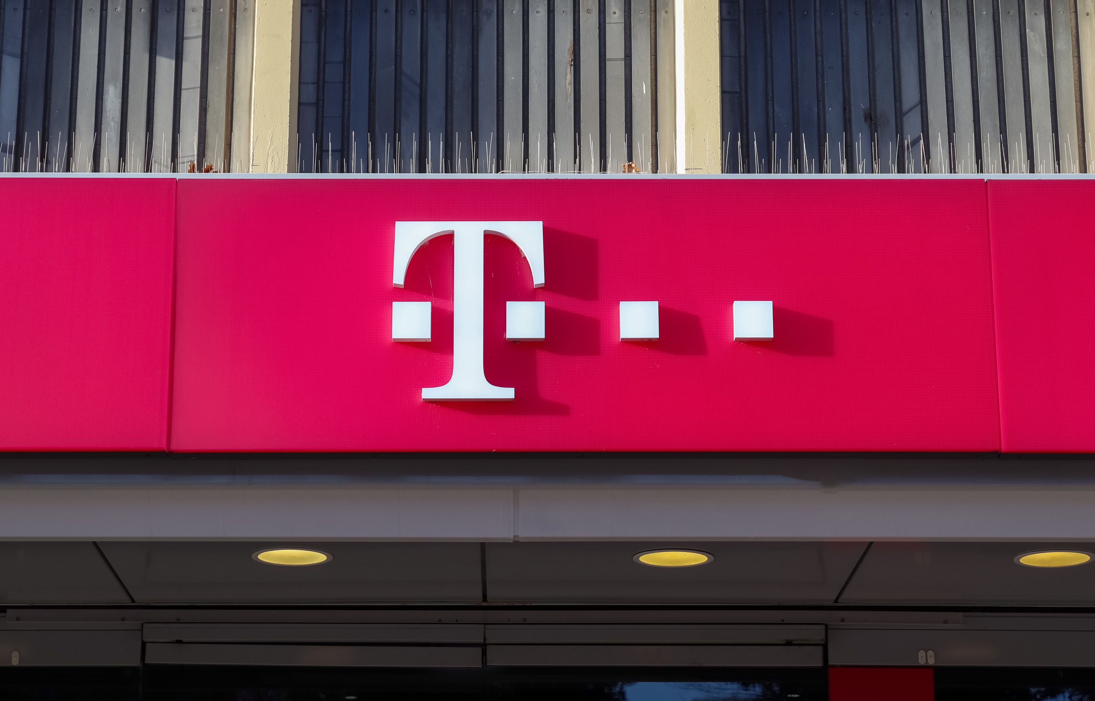 Logo der Deutschen Telekom auf einem pinken Schild an einer Hausfassade.