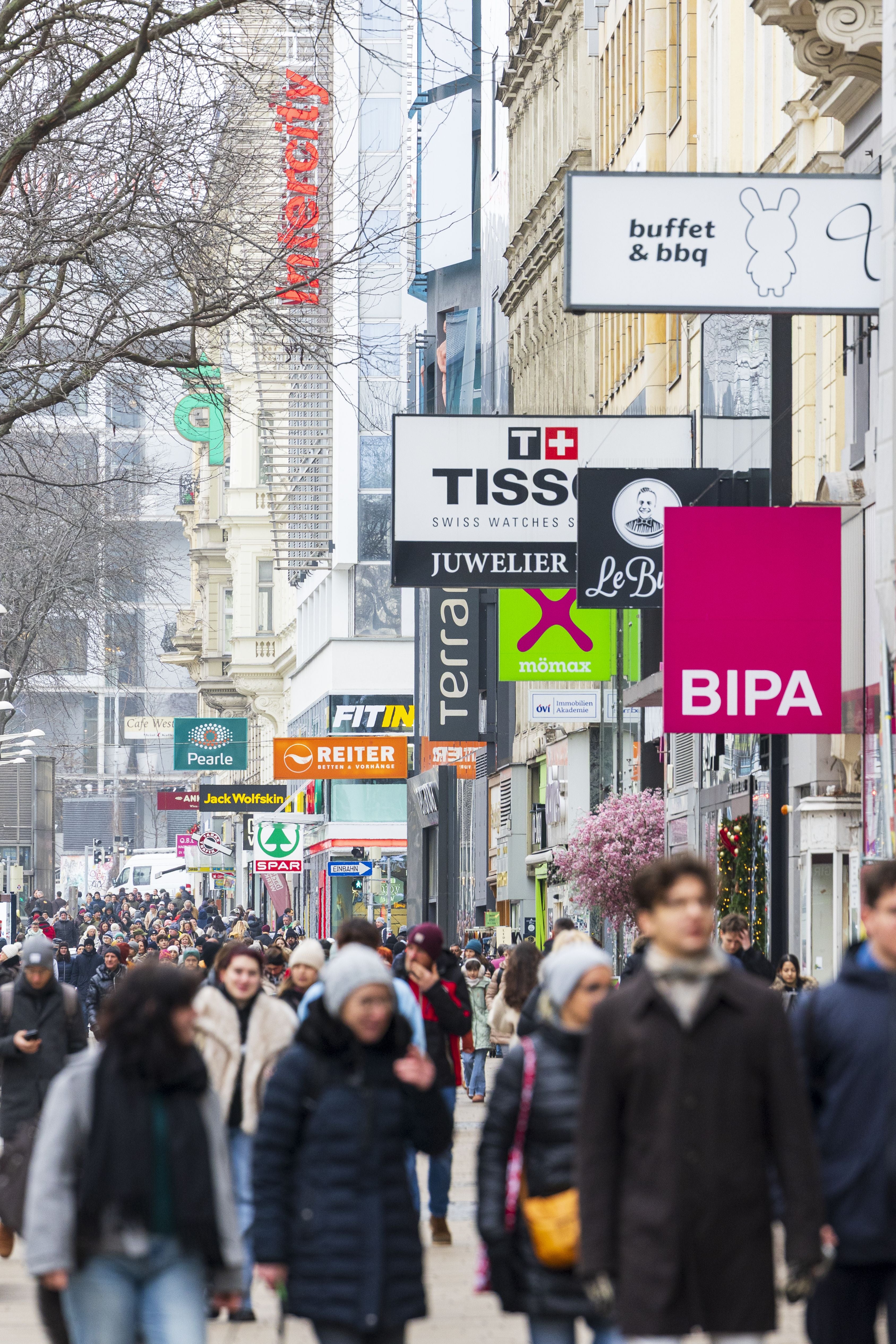 Viele Menschen spazieren und shoppen auf der belebten Mariahilfer Straße in Wien.