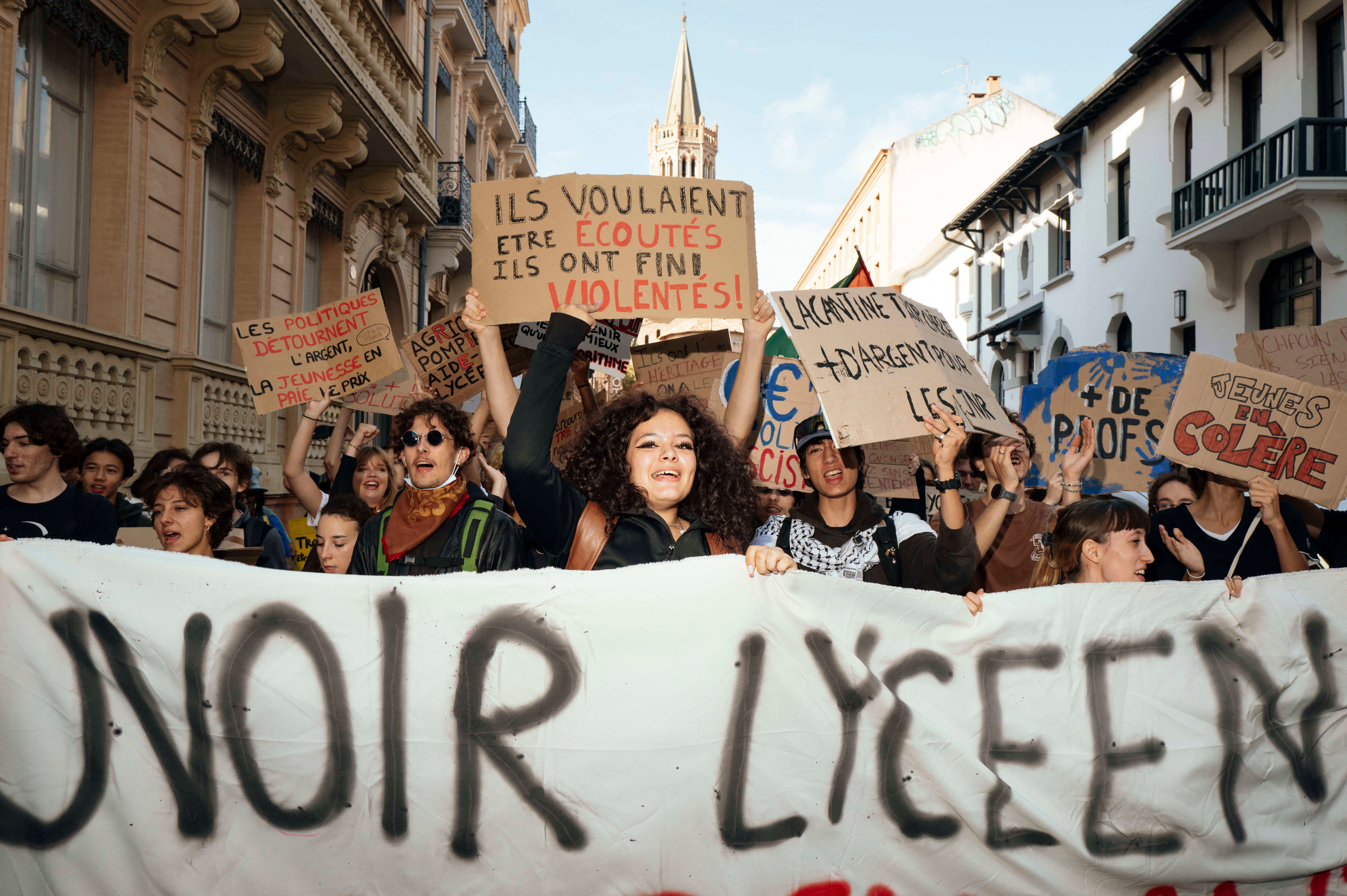 Schülerinnen und Schüler protestieren mit Transparenten und Plakaten in einer Straße in Toulouse.