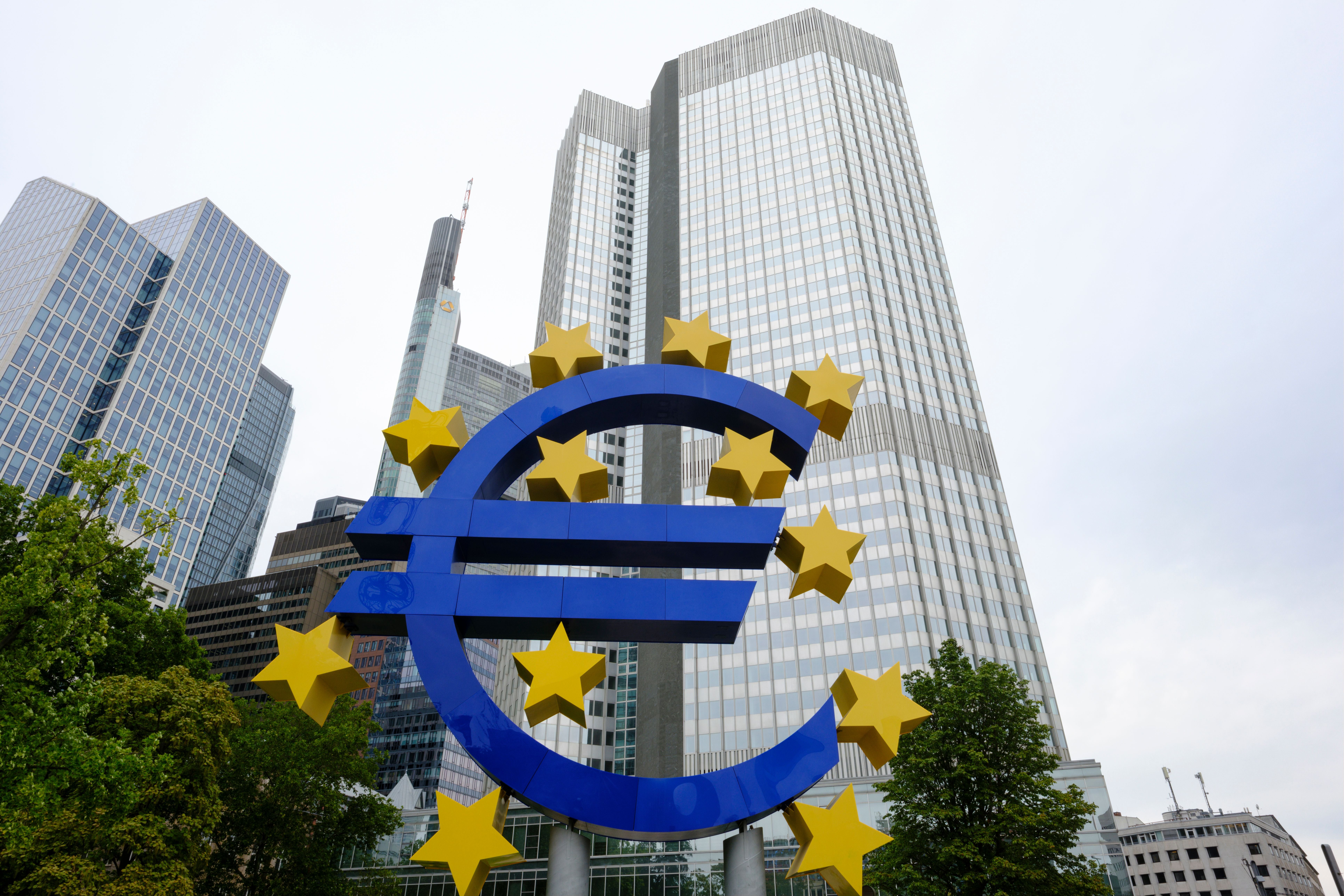 Großes Euro-Zeichen vor Hochhäusern in Frankfurt am Main, umgeben von gelben Sternen.