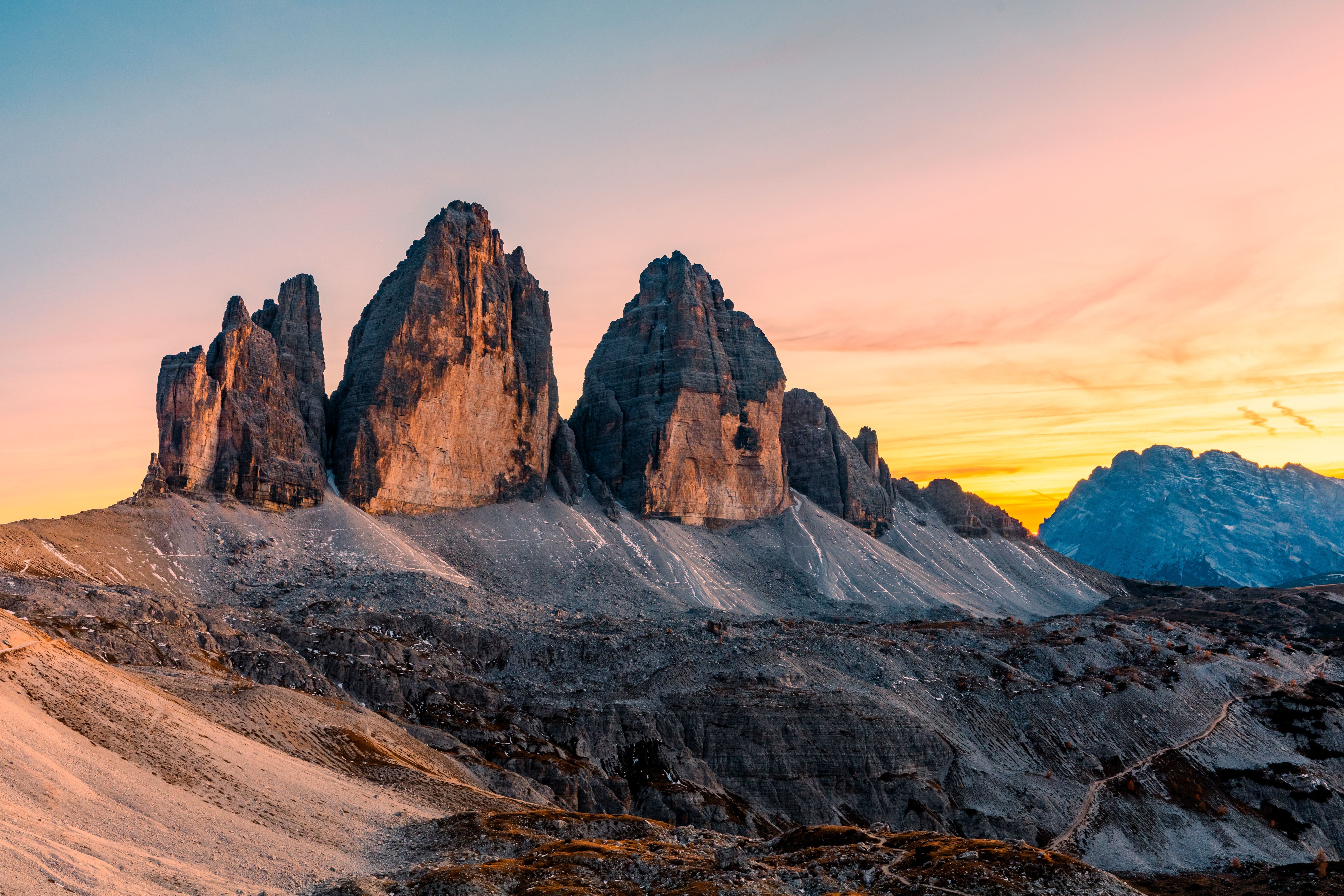 Die Drei Zinnen in den Dolomiten bei Sonnenuntergang mit orangefarbenem Himmel.