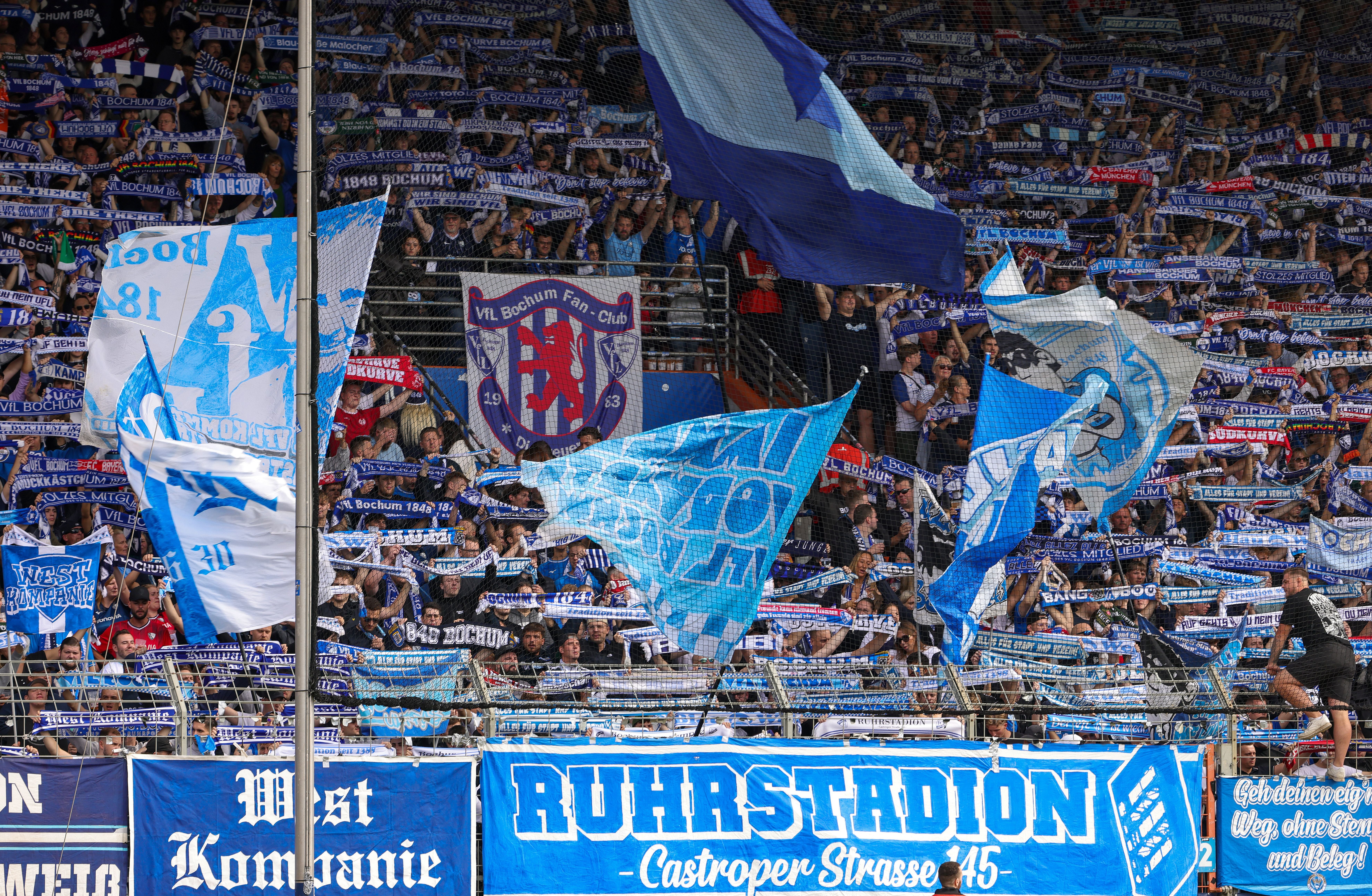 VfL Bochum-Fans schwenken Fahnen und halten Schals im Ruhrstadion während eines Fußballspiels.
