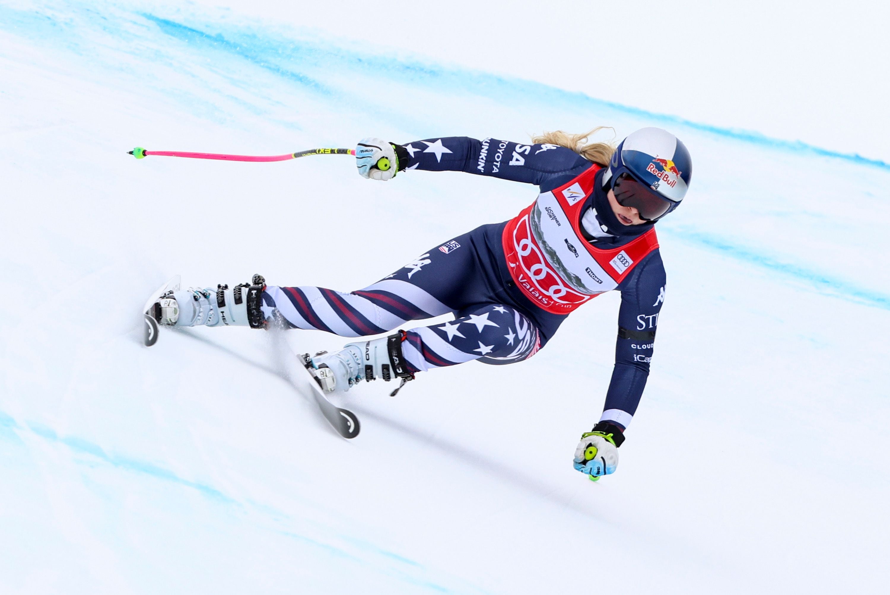 Eine Skirennläuferin fährt in voller Geschwindigkeit eine Abfahrt auf einer verschneiten Piste hinunter.