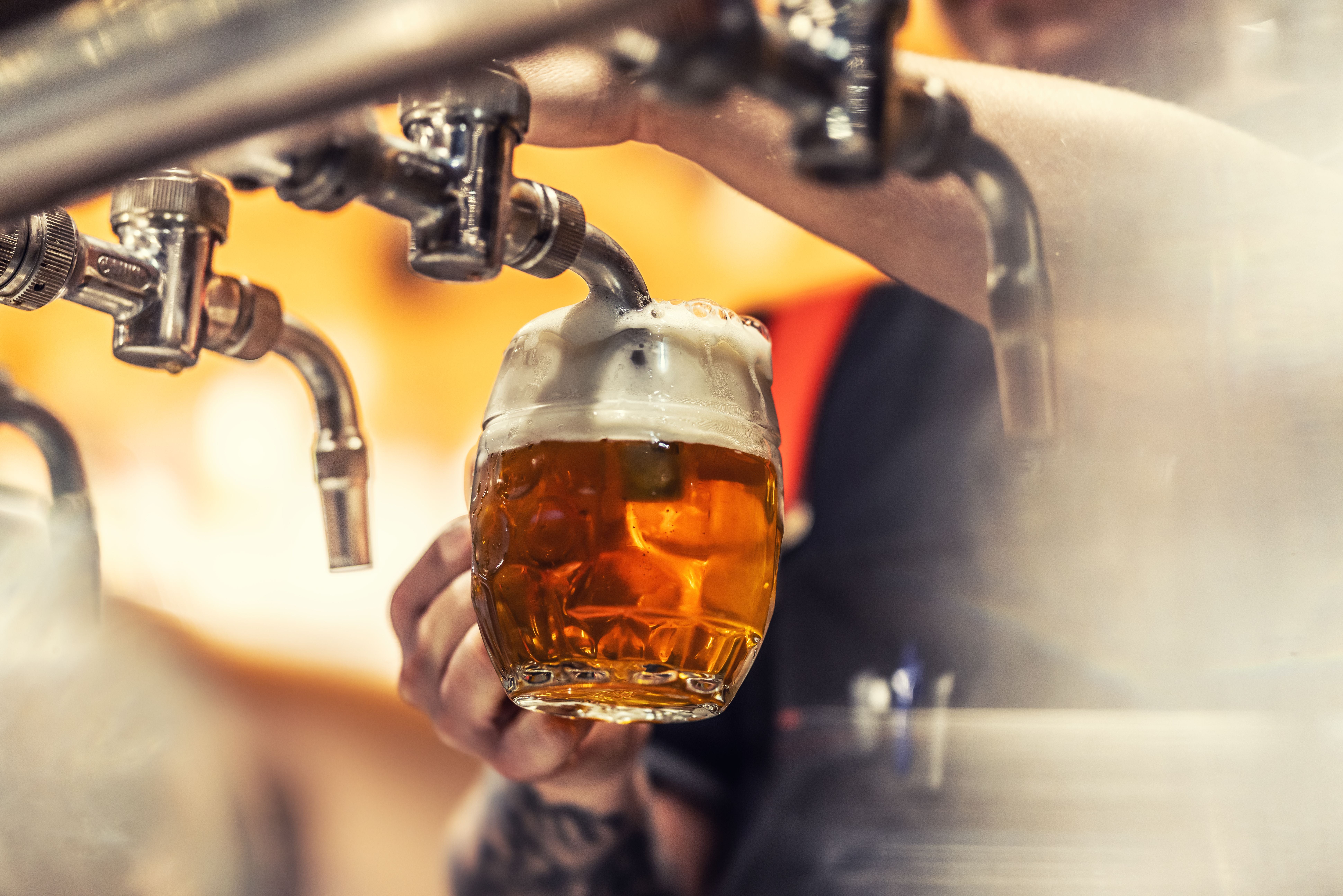 Nahaufnahme eines Bieres, das vom Zapfhahn ins Glas mit viel Schaum eingeschenkt wird.