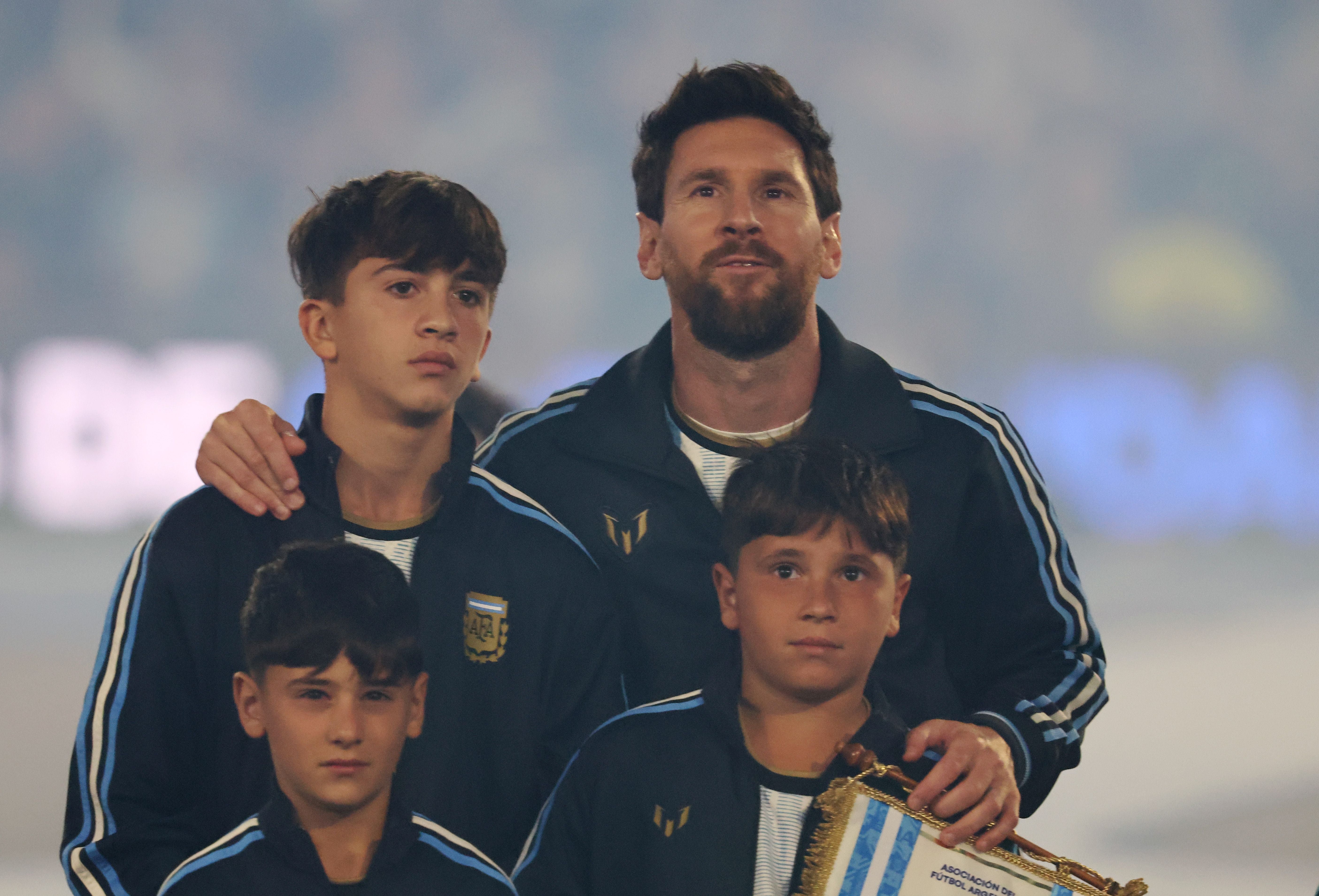 Lionel Messi steht mit seinen drei Söhnen vor einem Fußballspiel im Stadion.