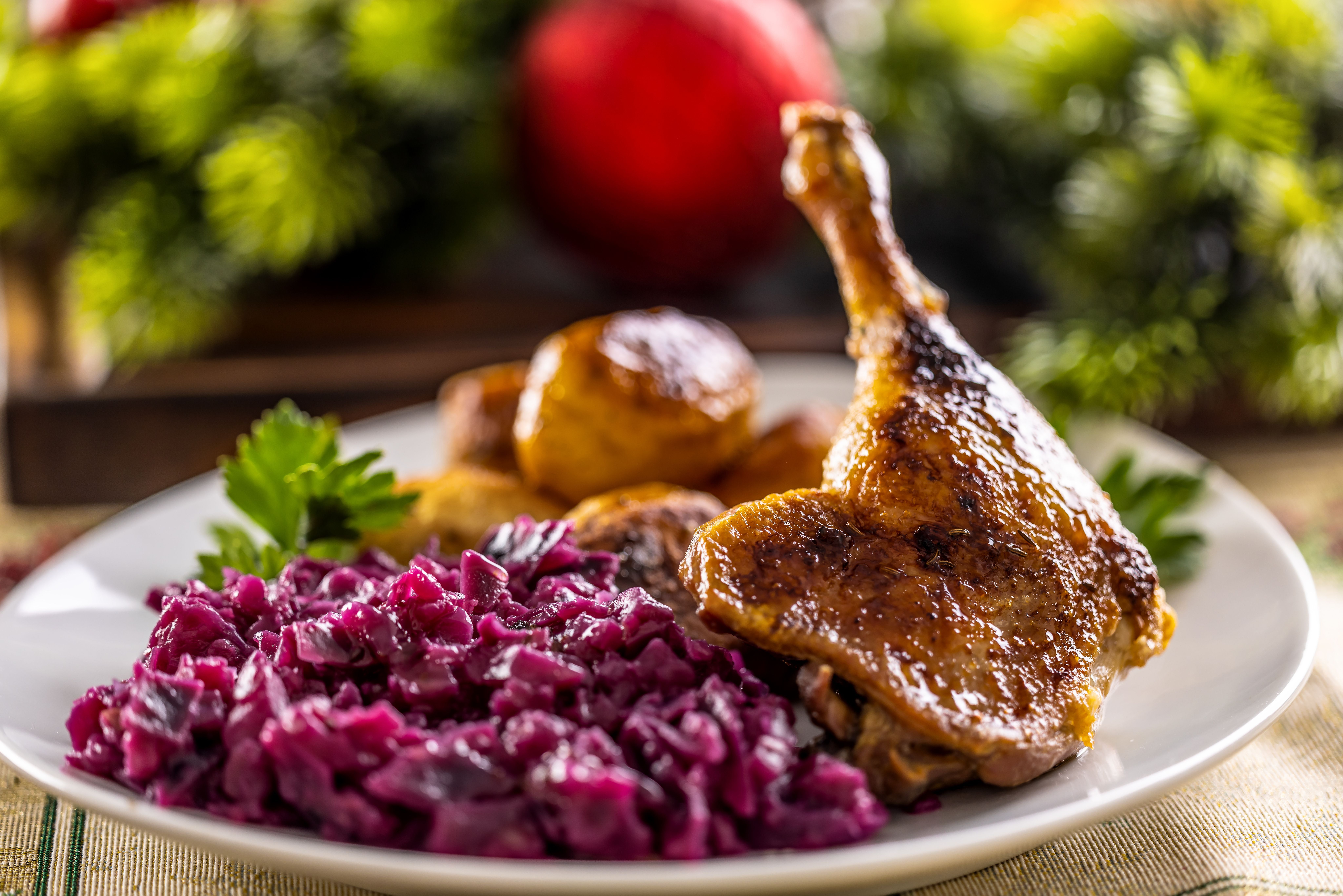 Gänsekeule mit Rotkohl und gebackenen Kartoffeln auf festlich gedecktem Weihnachtstisch.