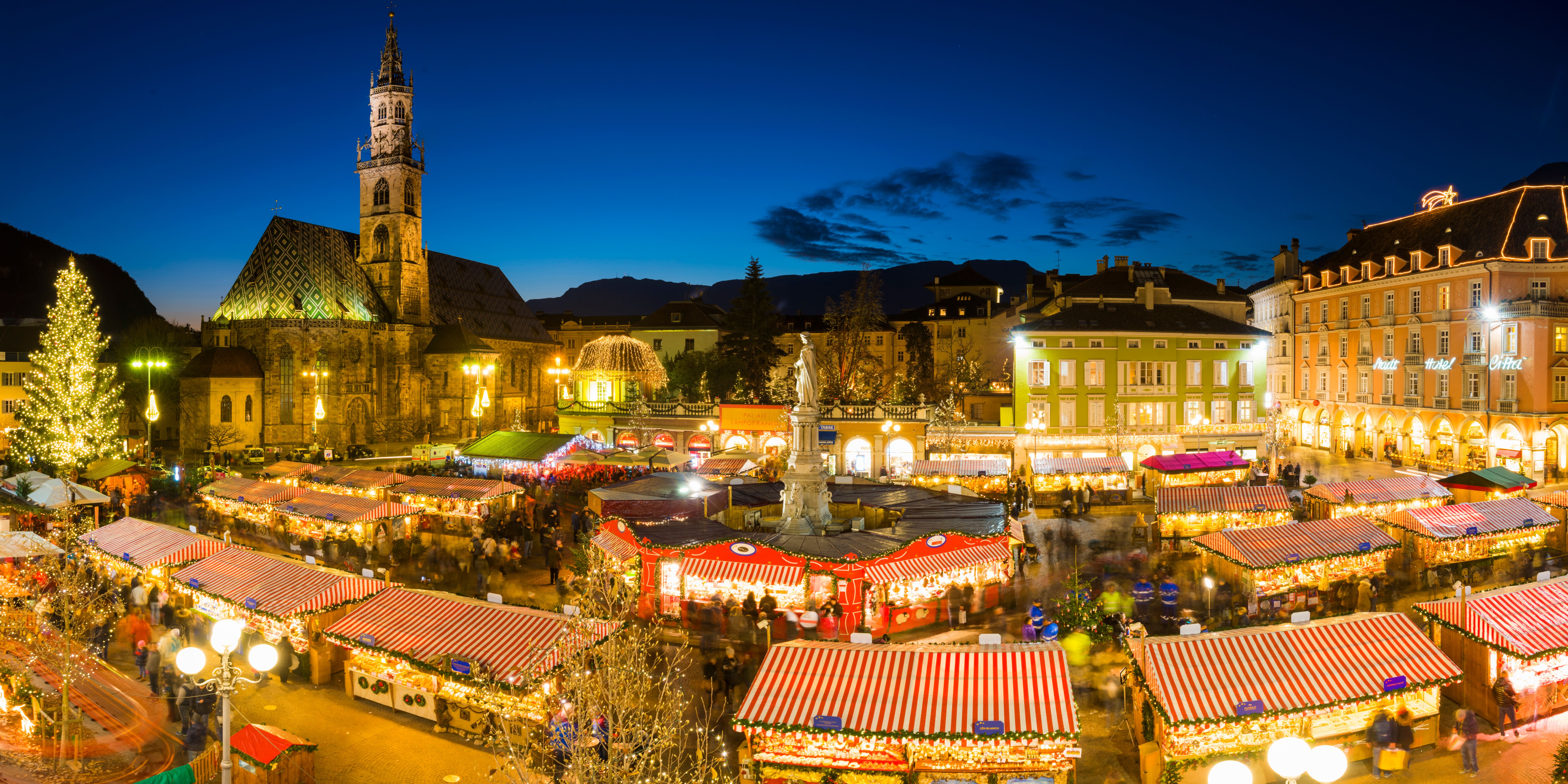 Weihnachtsmarkt am Waltherplatz bei Abenddämmerung mit beleuchteten Buden und Kirche im Hintergrund.