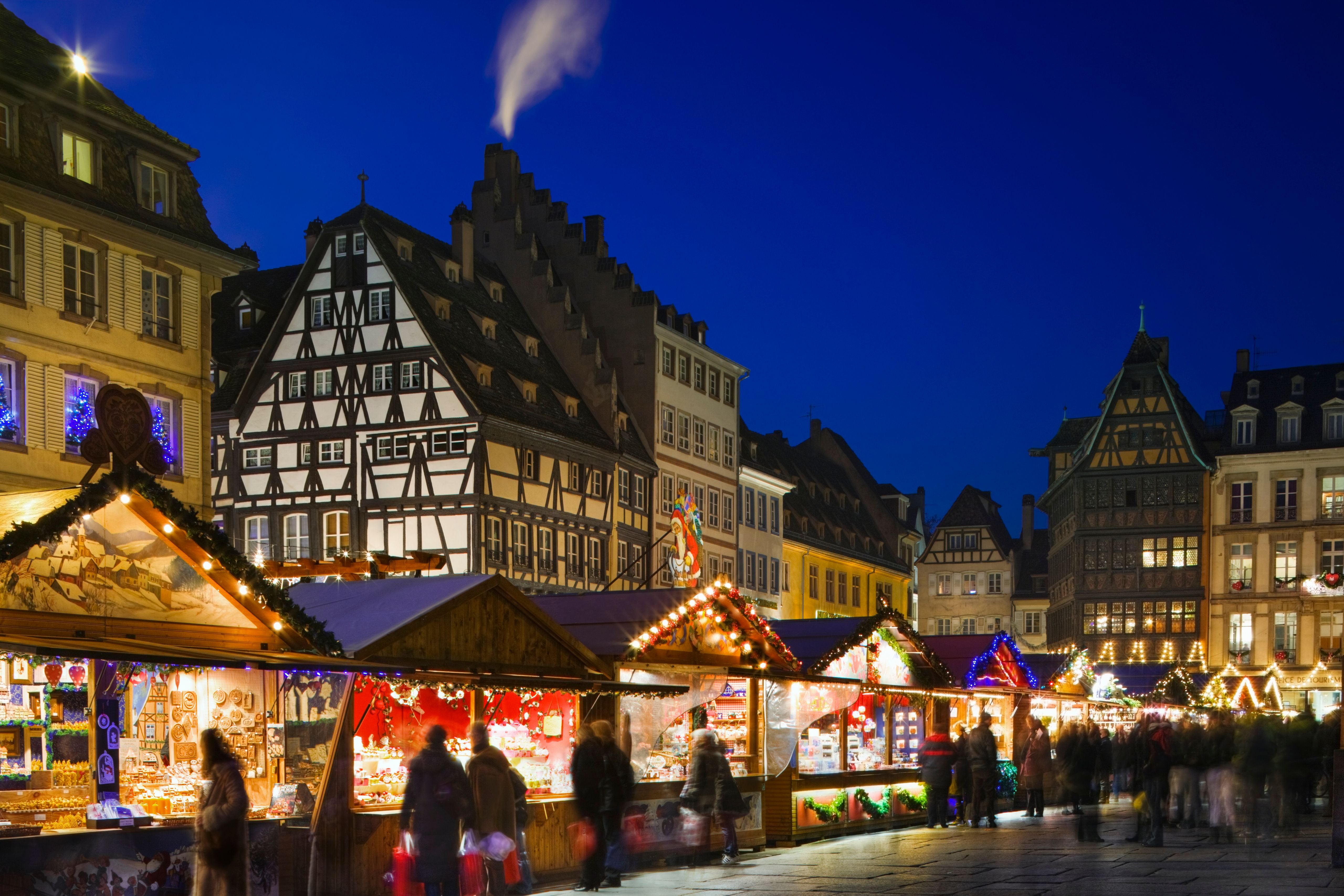 Weihnachtsmarkt am Abend mit festlich beleuchteten Buden und Fachwerkhäusern im Hintergrund.