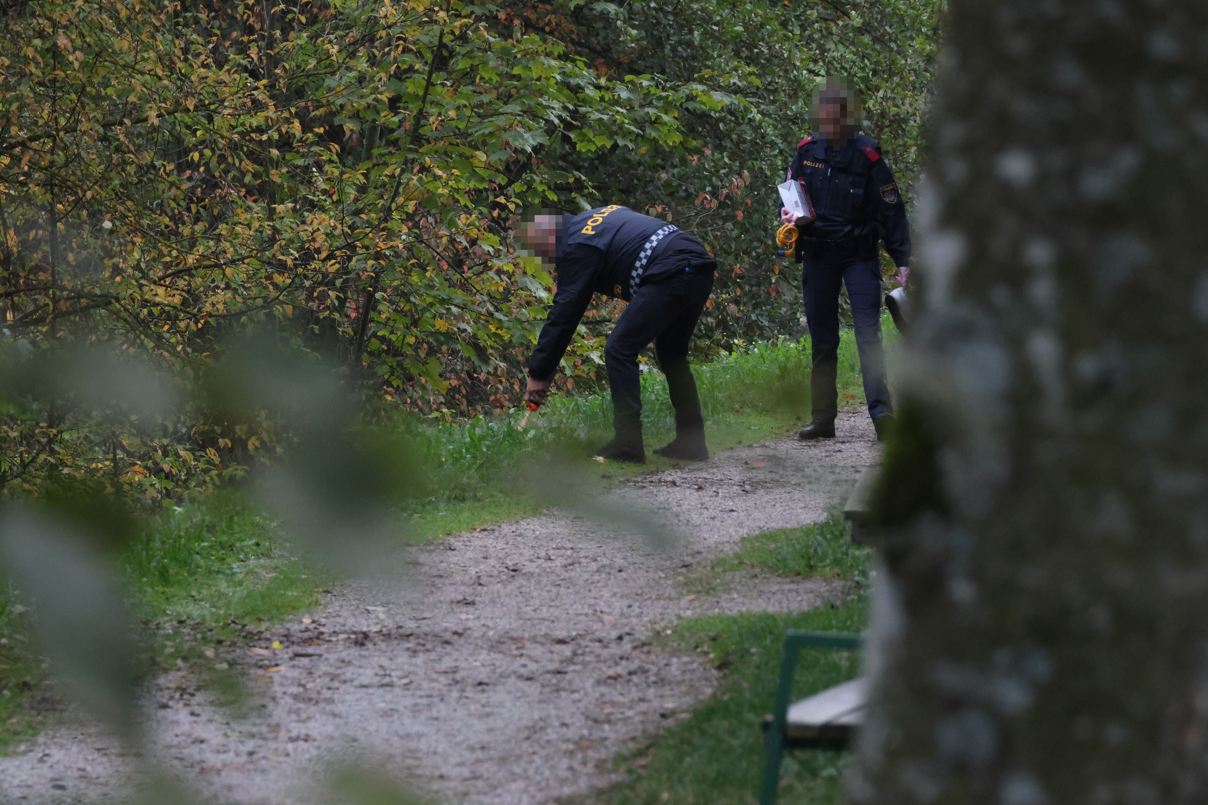 Zwei Polizisten untersuchen einen Weg im Grünen nach einem tödlichen Fahrradunfall.