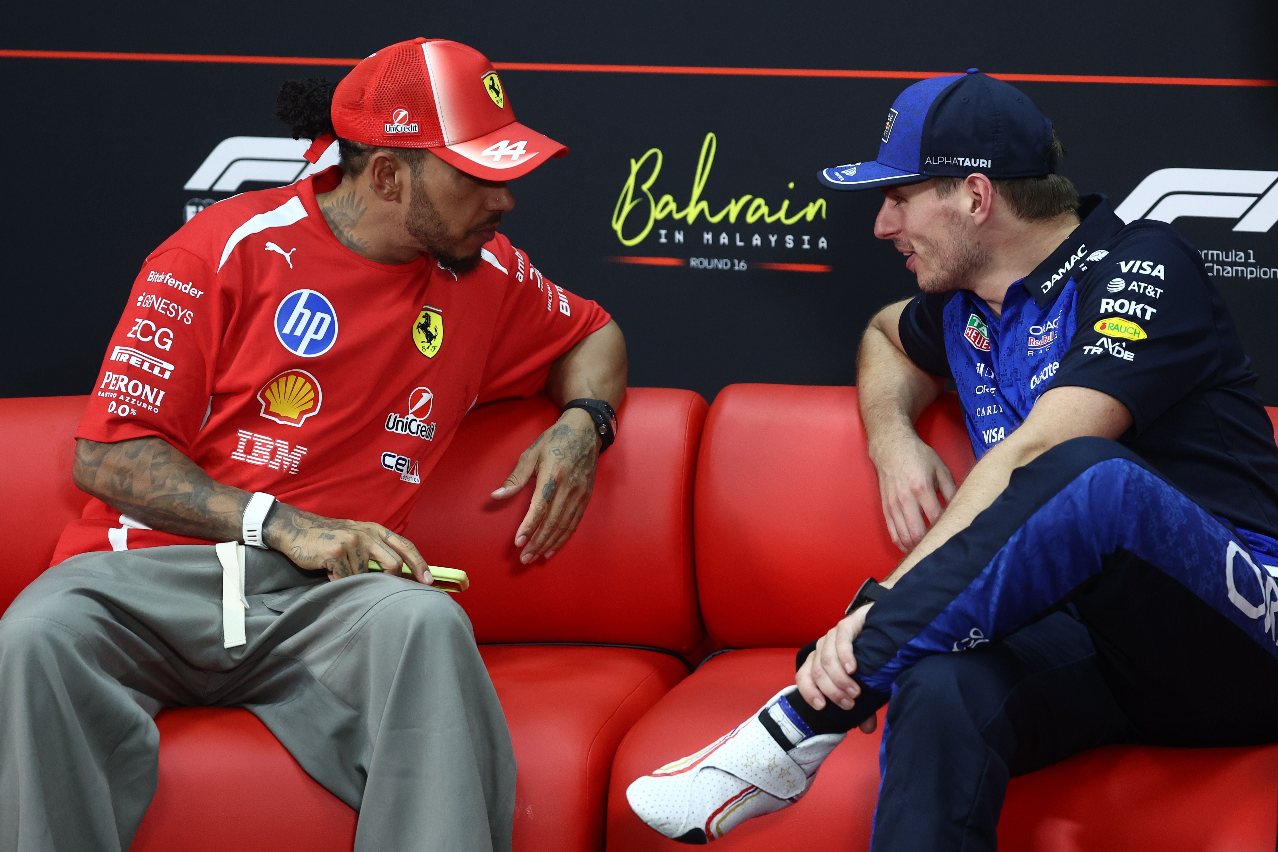 Zwei Formel-1-Fahrer unterhalten sich auf einem roten Sofa bei einer Pressekonferenz in Bahrain.