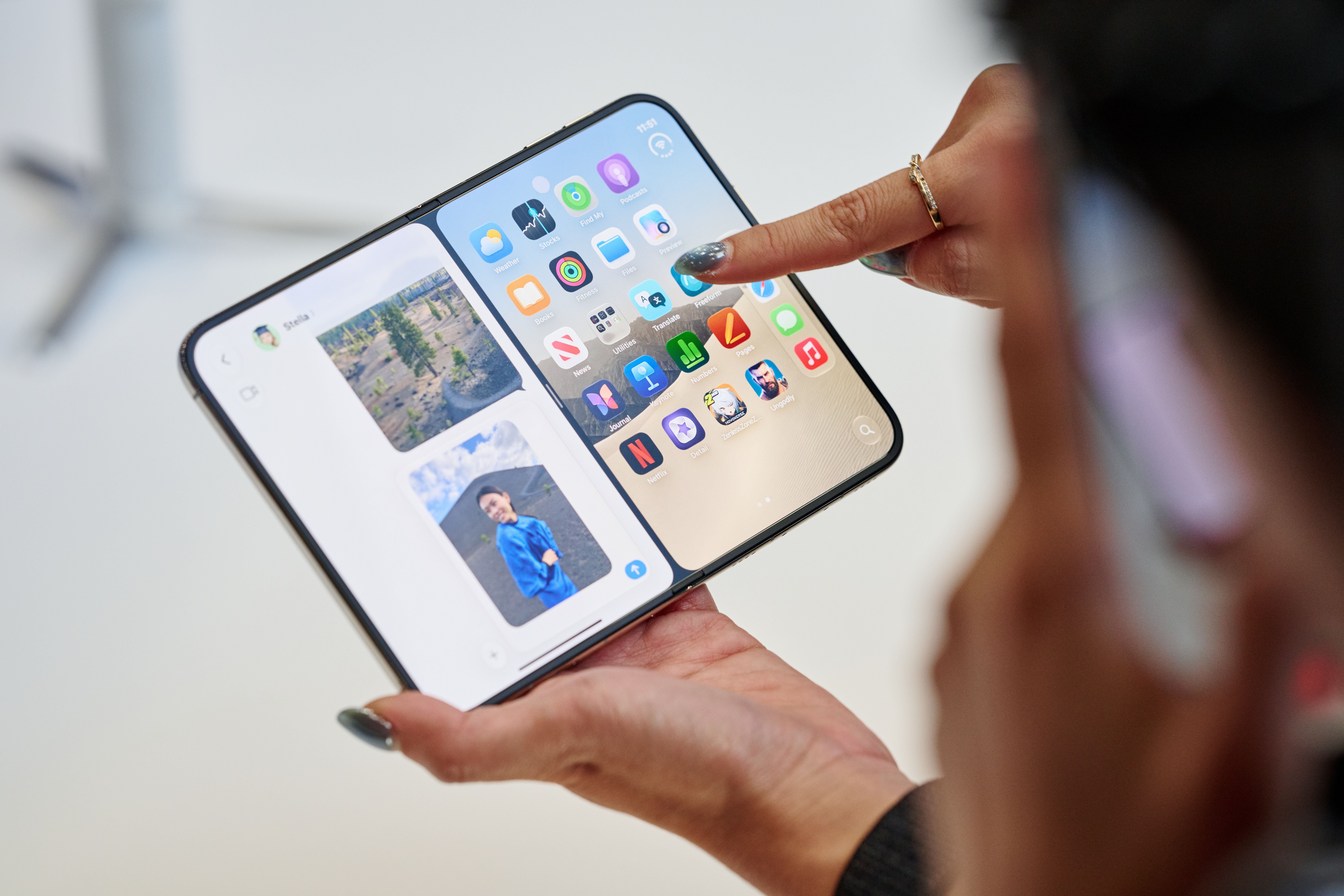 Eine Person hält ein aufklappbares iPhone mit zwei Bildschirmen und tippt auf das Display.