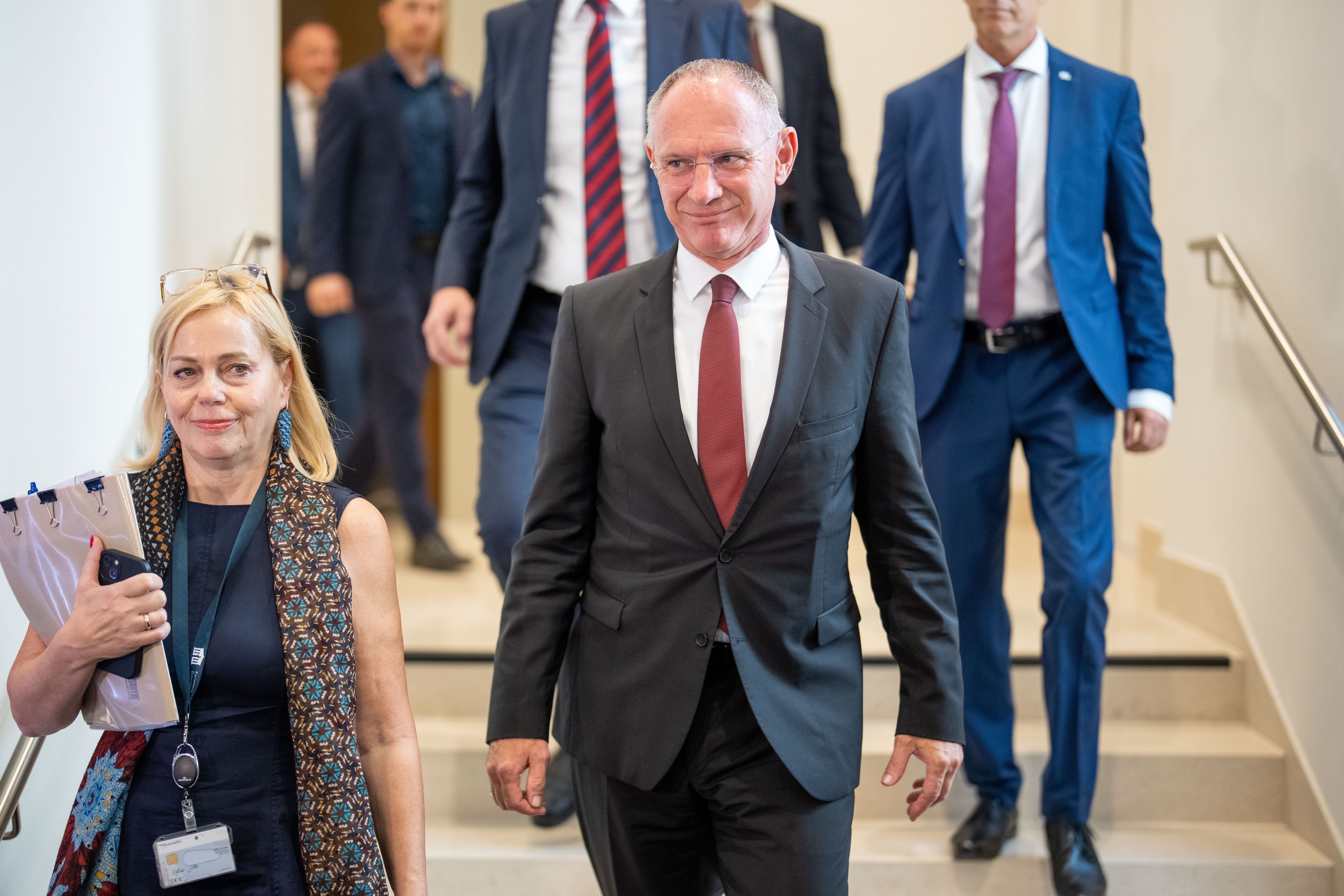 Gerhard Karner geht mit mehreren Personen eine Treppe im Parlament in Wien hinunter.