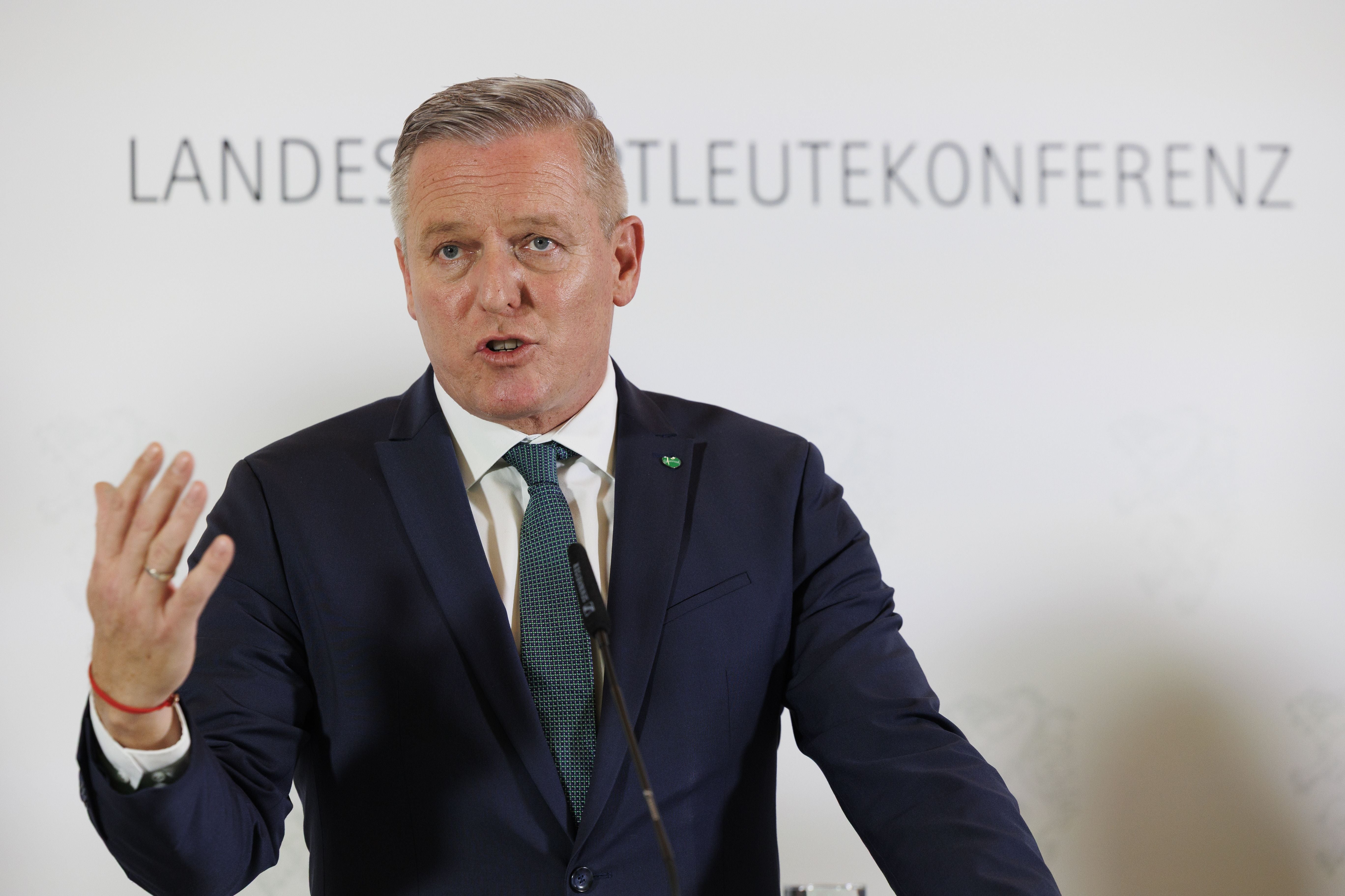 Ein Mann im Anzug spricht auf einer Pressekonferenz vor einem Schild "Landeshauptleutekonferenz".