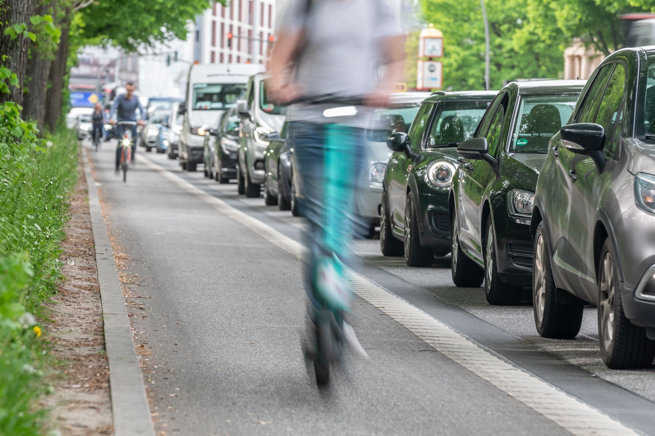 Ein E-Scooter fährt auf dem Radweg an im Stau stehenden Autos vorbei.