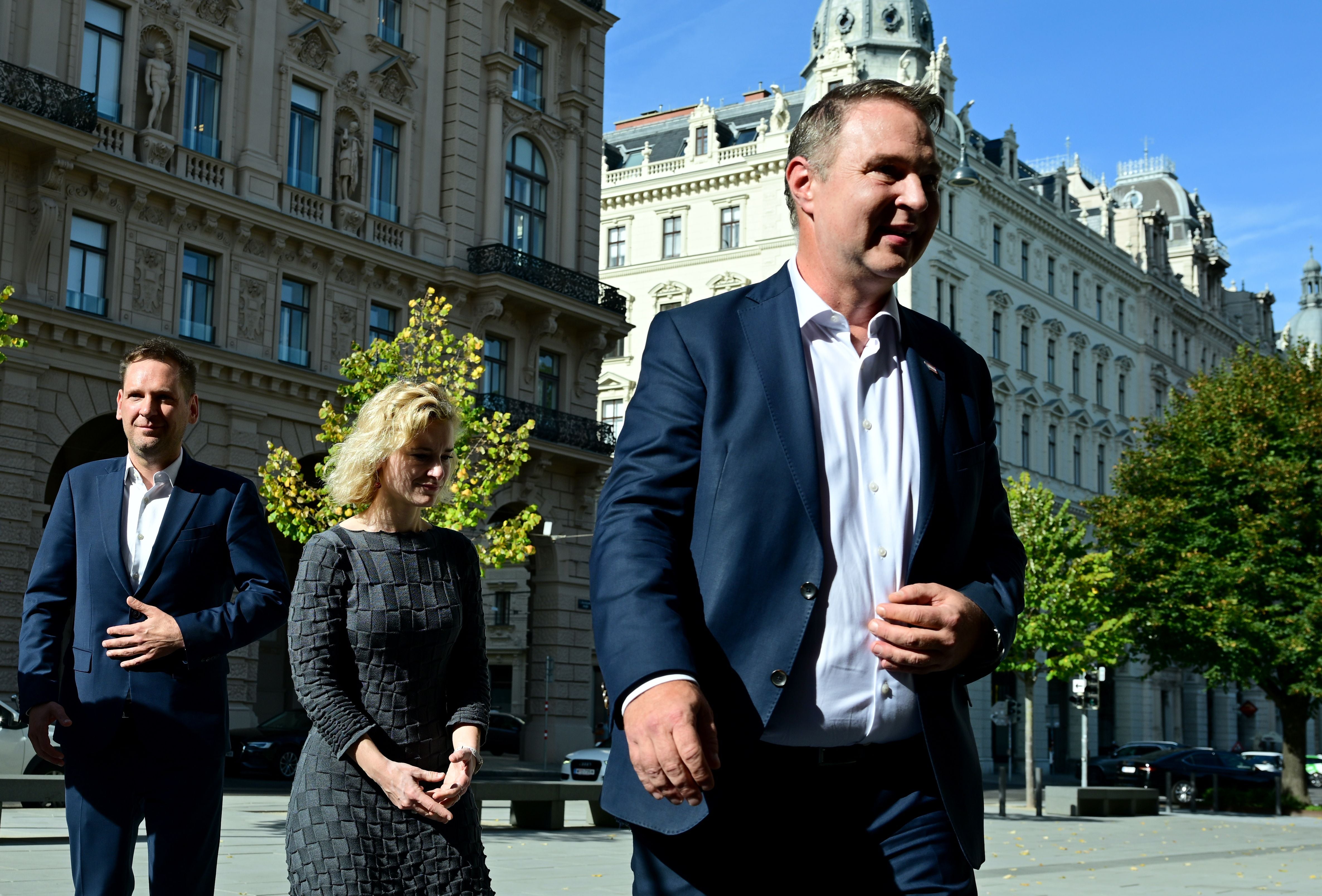 Drei Personen im Business-Outfit gehen vor historischen Gebäuden in Wien entlang.