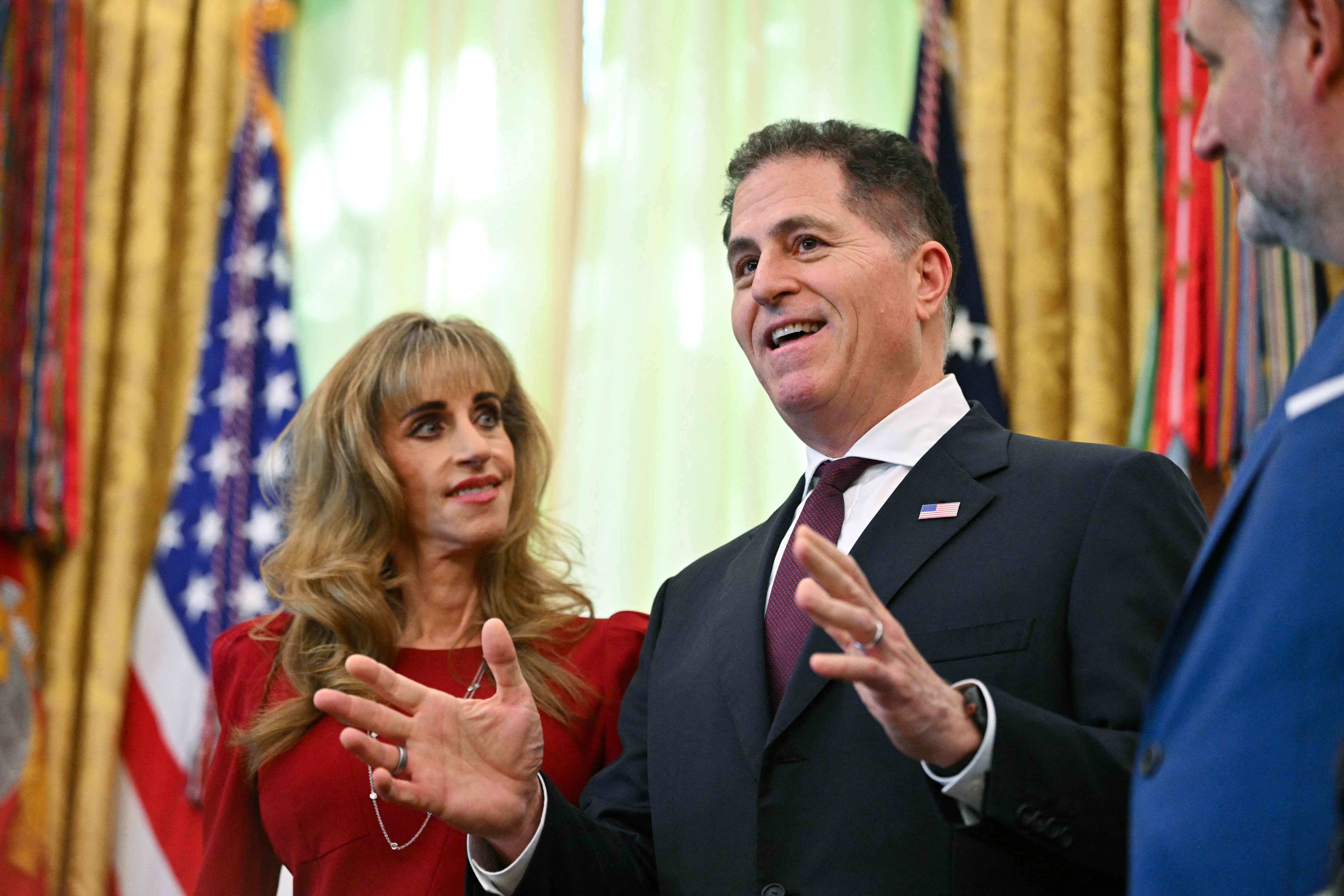 Ein Mann im Anzug spricht gestikulierend neben einer Frau im roten Kleid im Oval Office.