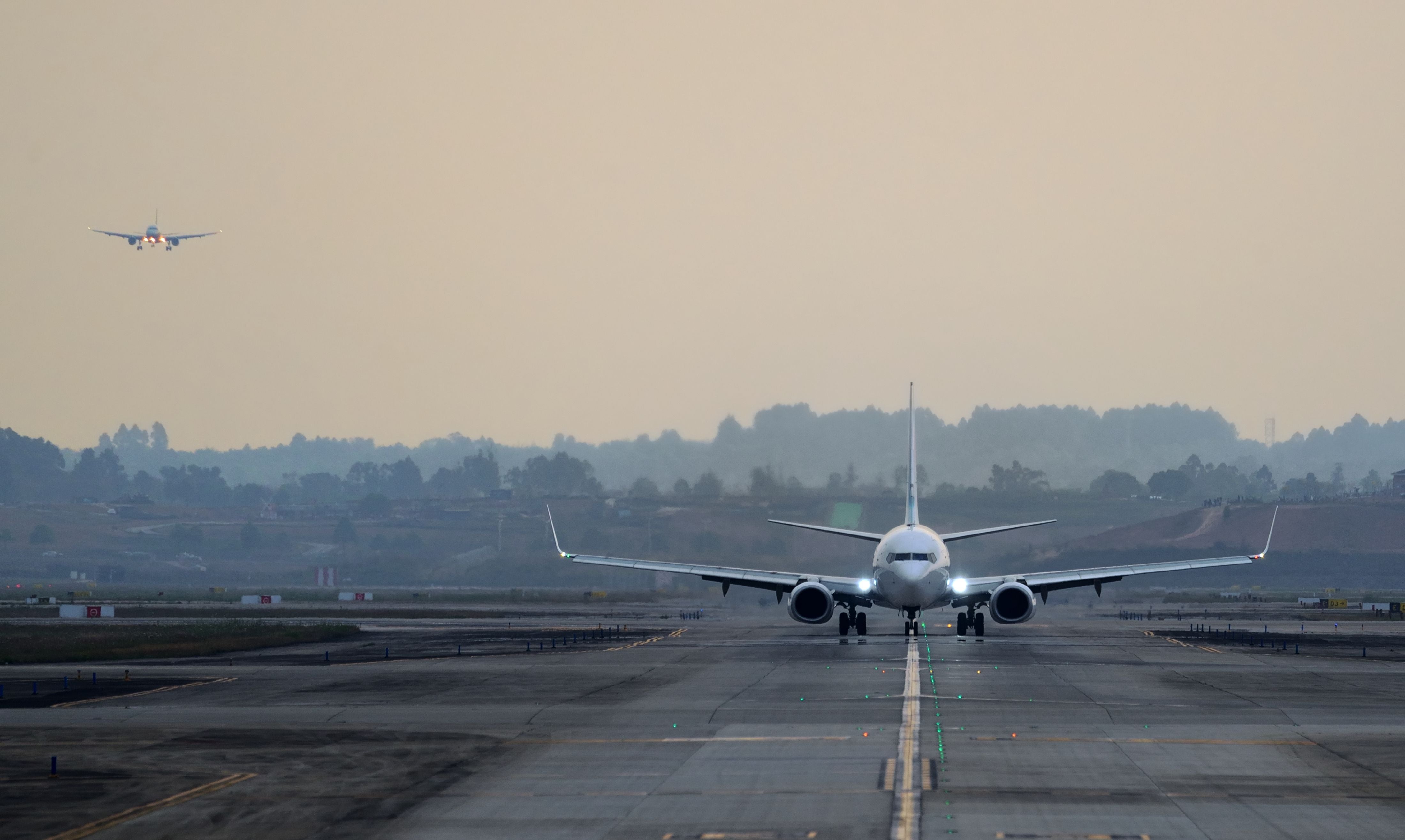 Ein Flugzeug rollt auf der Landebahn, im Hintergrund landet ein weiteres Flugzeug.