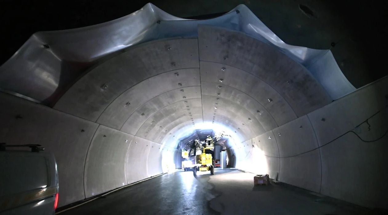 Beleuchteter Straßentunnel in Norwegen mit Fahrzeug und Bauausrüstung im Inneren.