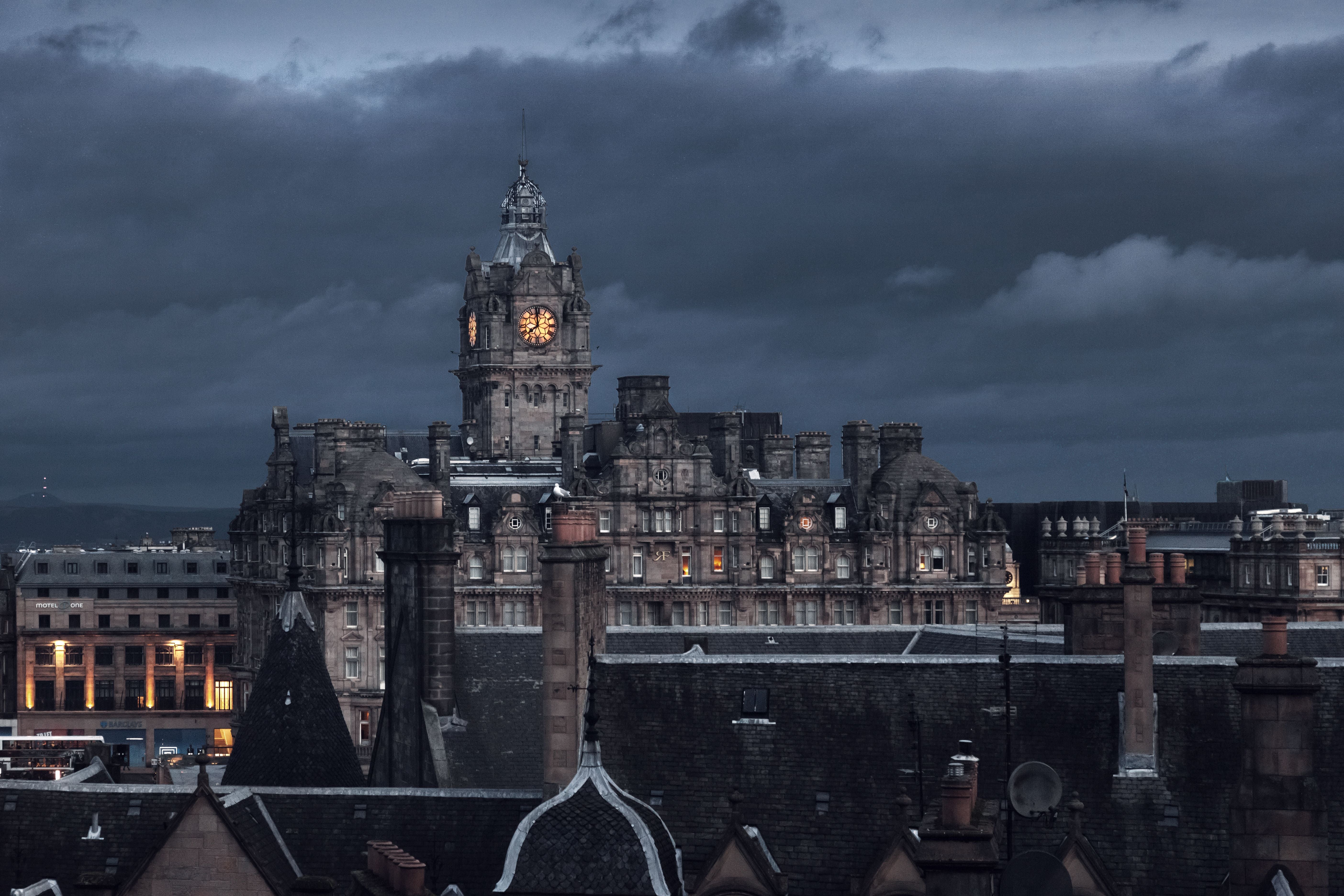 Blick auf Edinburgh bei Dunkelheit mit beleuchtetem Uhrturm und historischen Gebäuden.