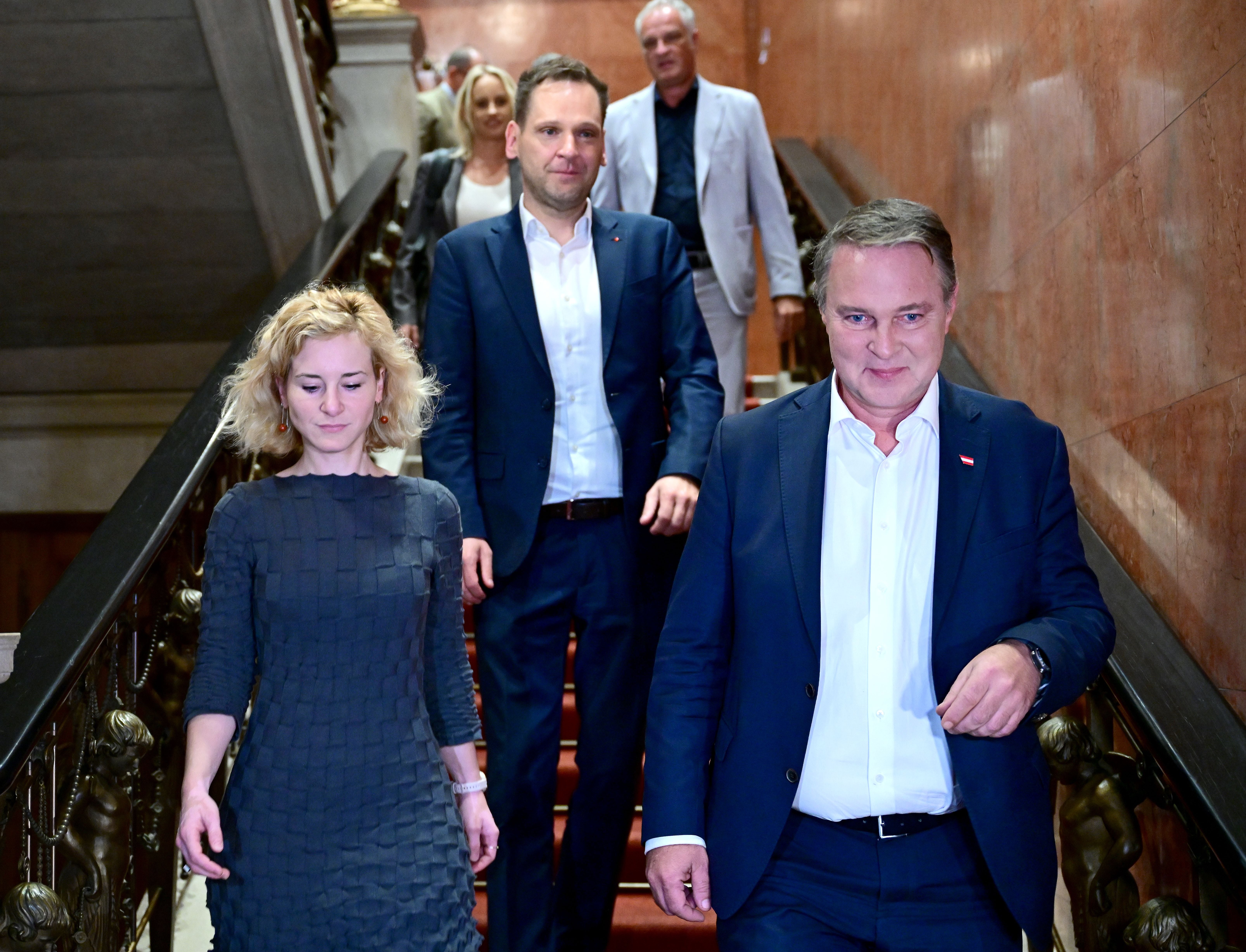 Mehrere Personen in formeller Kleidung gehen eine Treppe in einem Gebäude hinunter.