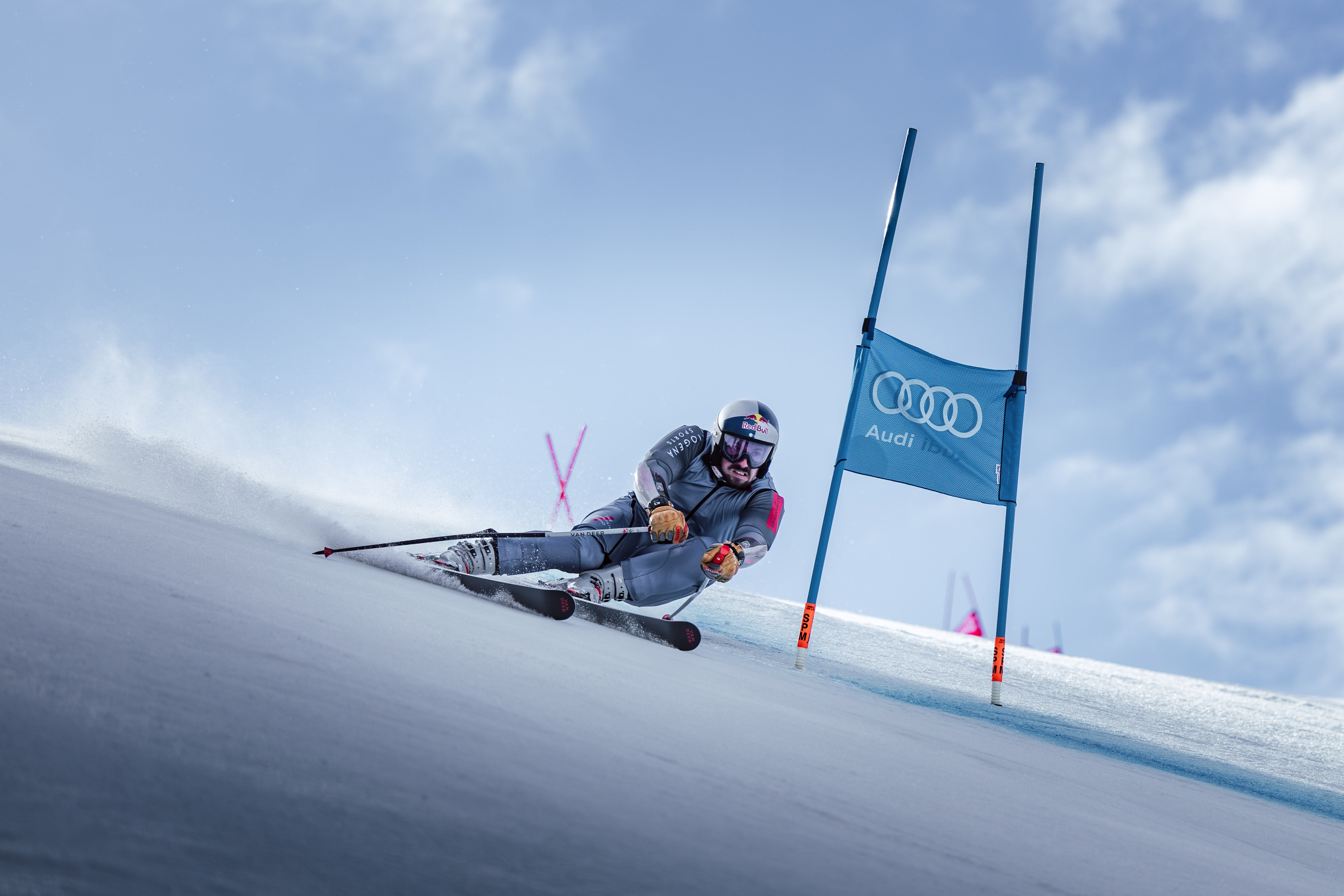 Ein Skirennläufer fährt eine Slalomkurve um eine blaue Torstange mit Audi-Logo.