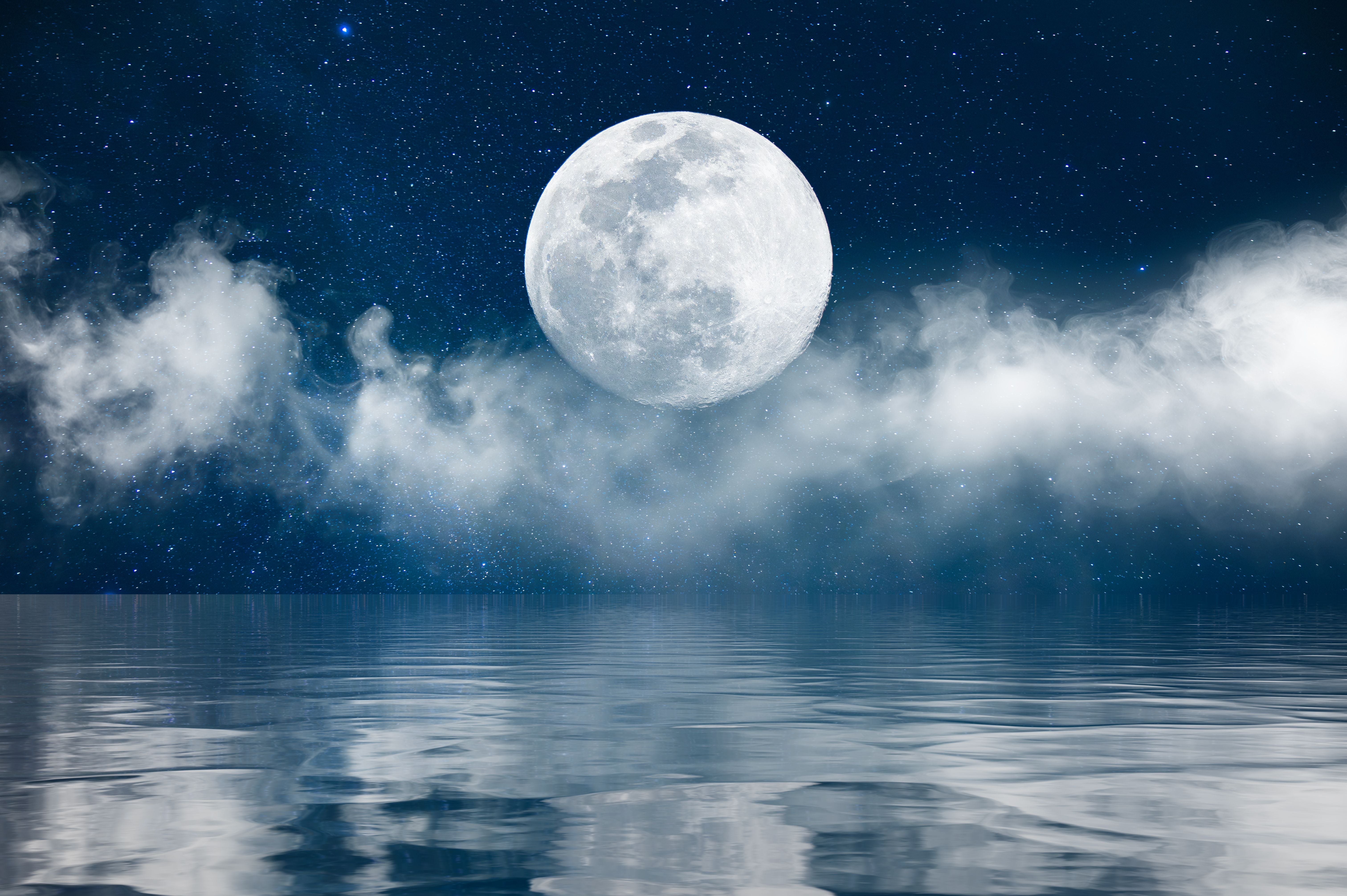 Vollmond am Nachthimmel mit Wolken und Spiegelung im ruhigen Wasser darunter.