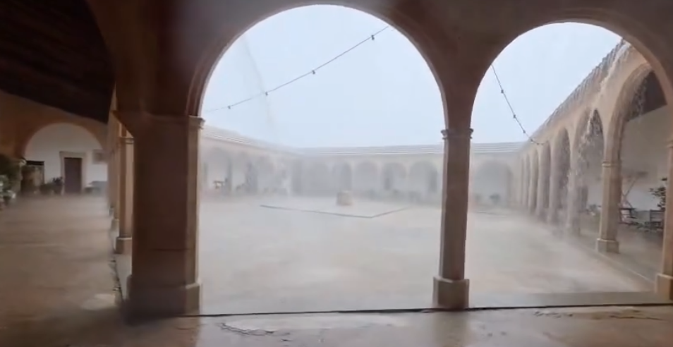 Starker Regen fällt in einen historischen Arkadenhof auf Mallorca.
