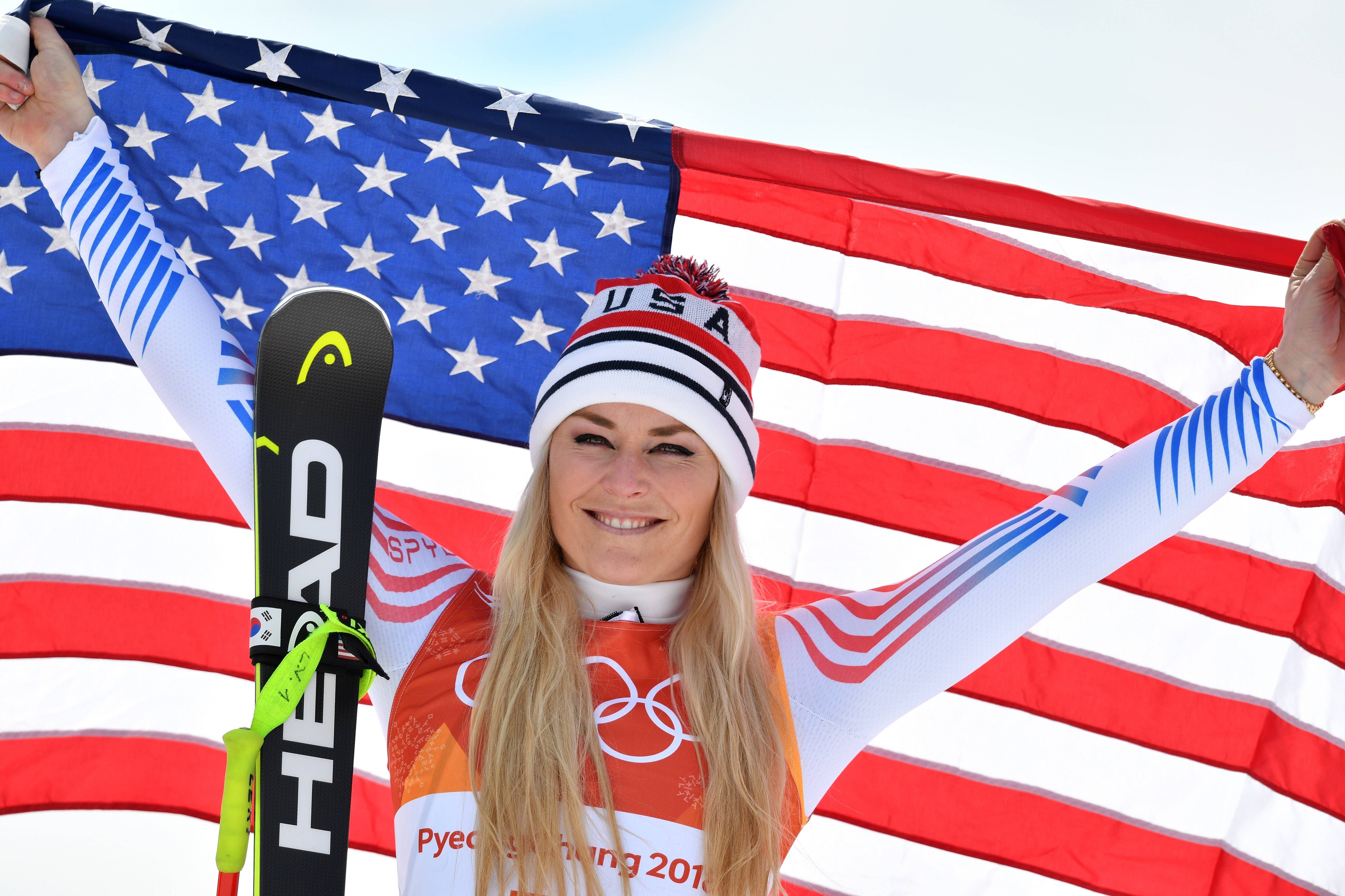Skifahrerin jubelt mit US-Flagge und Skiern bei den Olympischen Winterspielen 2018.