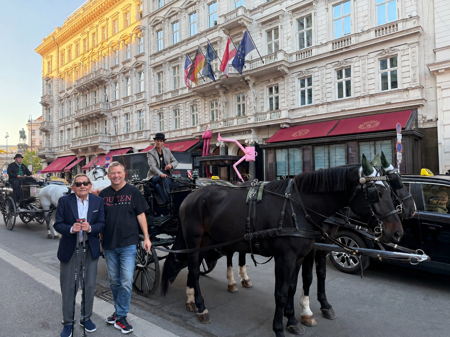 Zwei Männer stehen vor einer Pferdekutsche vor dem Hotel Sacher in Wien.
