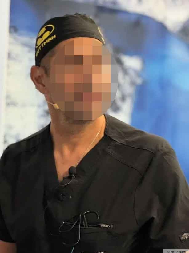 Ein Mann in schwarzer Kleidung und Mütze steht vor einem unscharfen blauen Hintergrund.