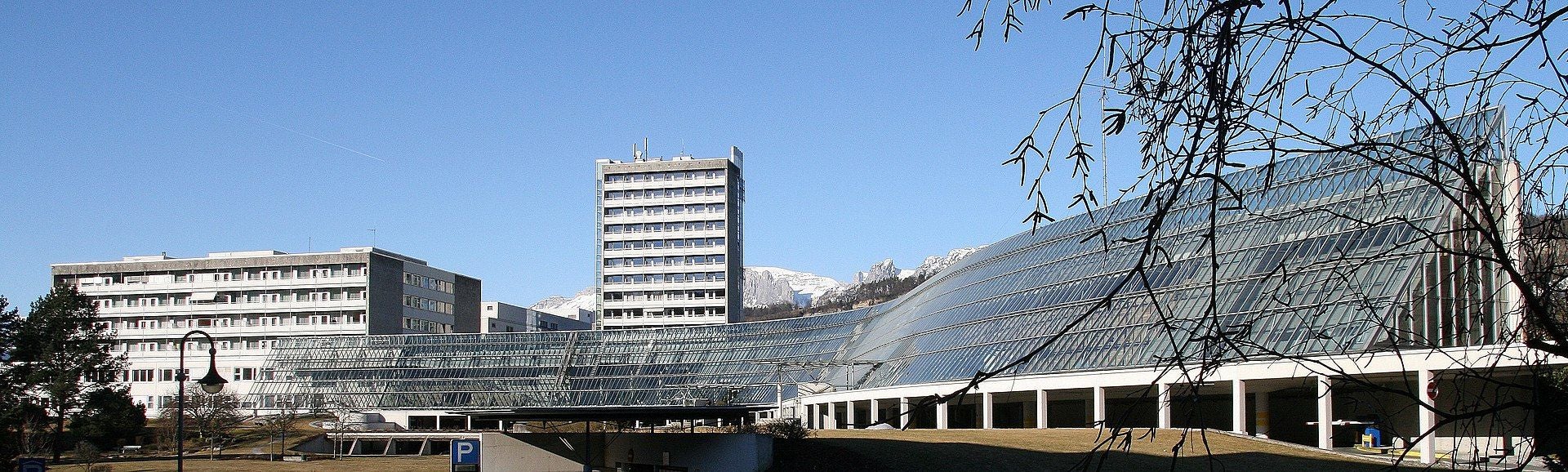 Krankenhauskomplex LKH Feldkirch mit moderner Glasfassade und Bergen im Hintergrund.