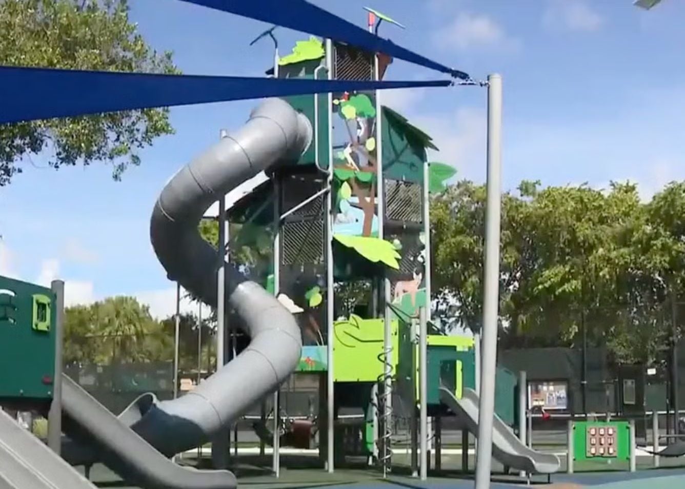 Großer Spielplatz mit Kletterturm und mehreren Rutschen, darunter eine lange, gewundene Röhrenrutsche.