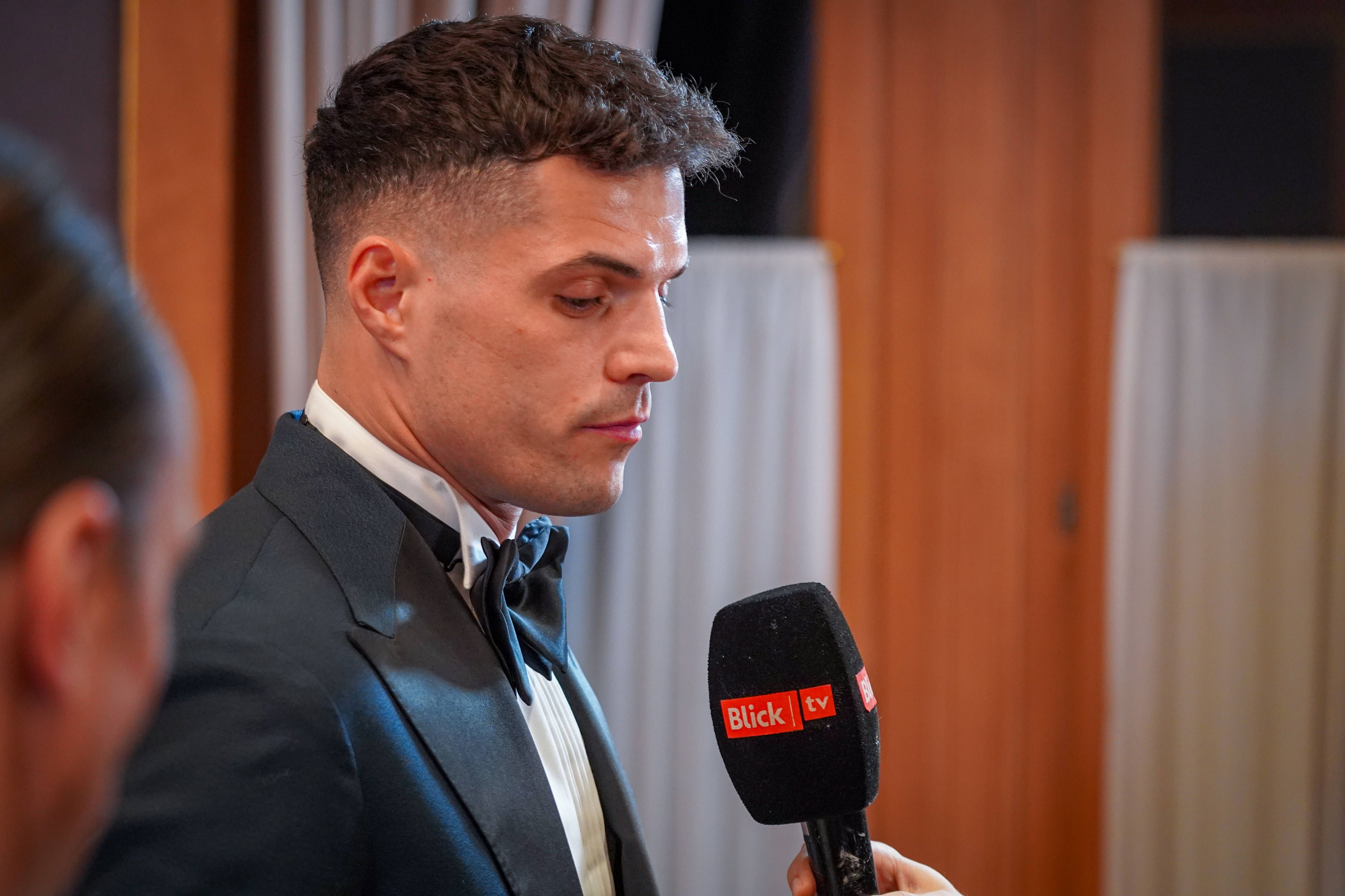 Granit Xhaka im dunklen Anzug mit Fliege blickt während einer Ansprache nach unten.