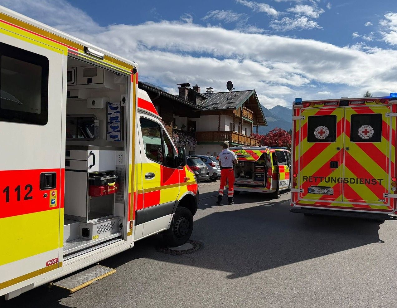 Mehrere Rettungsfahrzeuge und Sanitäter bei einem Einsatz auf einer Straße vor Wohnhäusern.