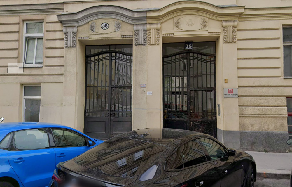 Zwei verzierte Hauseingänge mit Eisentoren, Hausnummern 38 und 40, davor geparkte Autos.