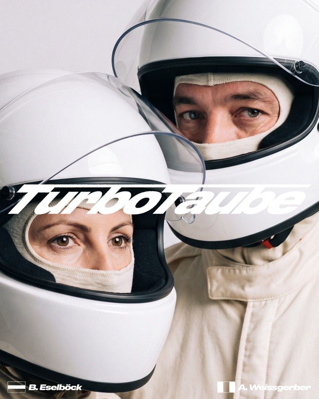 Zwei Personen in weißen Rennanzügen und Helmen, mit Schriftzug "Turbotaube" darüber.