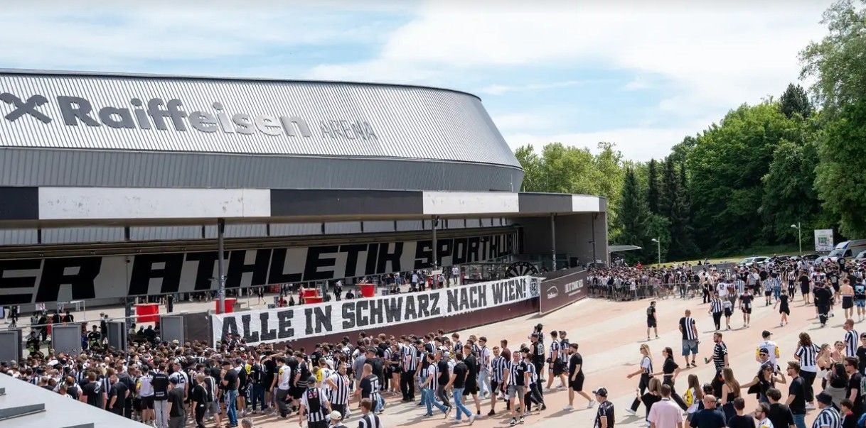 Die moderne Raiffeisen Arena auf der Linzer Gugl bei Nacht mit beleuchteter Fassade und gefüllten Rängen.