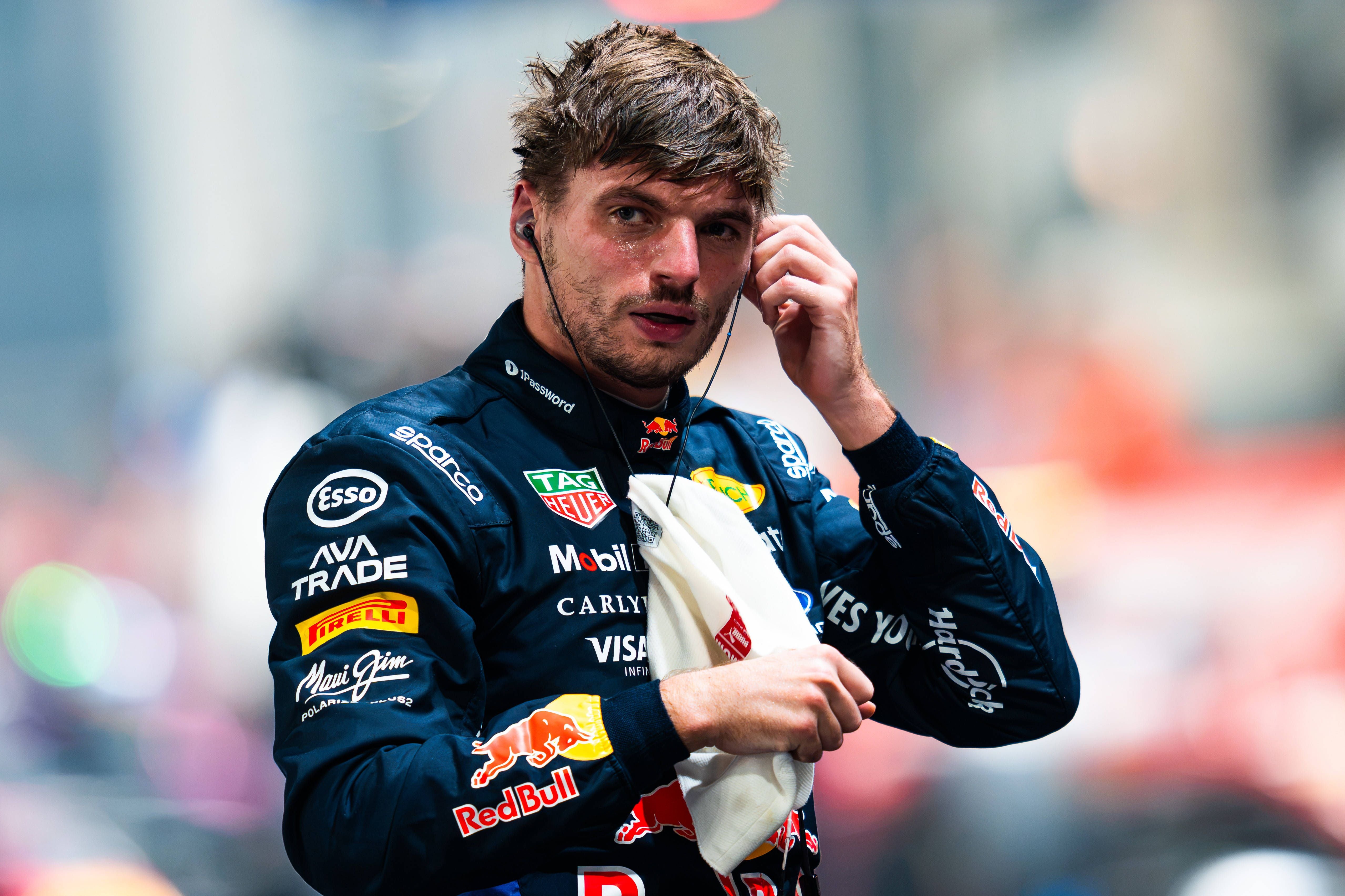 Ein Formel-1-Fahrer im Red Bull Overall steckt sich am Boxengasseneingang einen Ohrstöpsel ins Ohr.