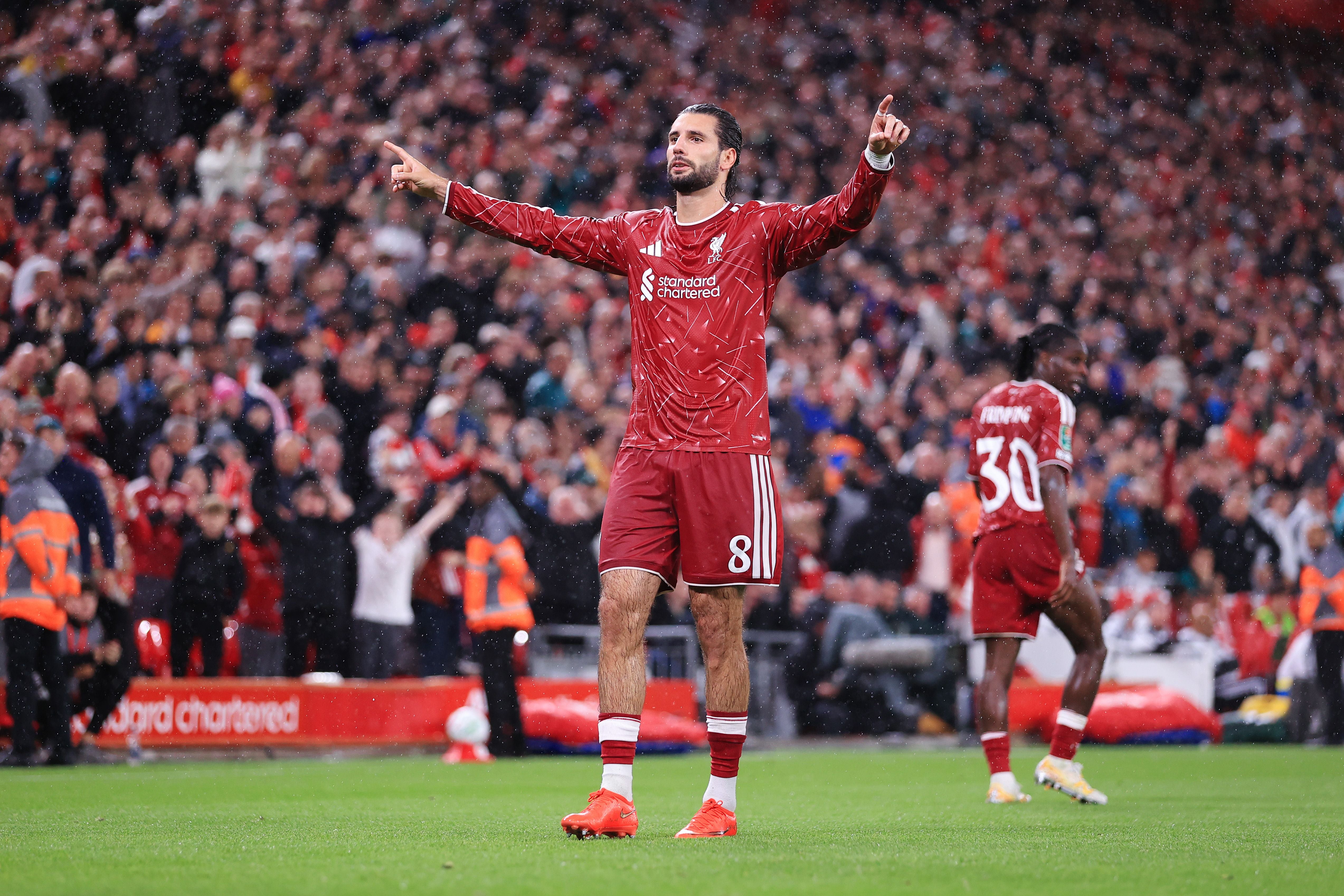 Liverpool-Profi Dominik Szoboszlai feiert im roten Trikot mit erhobenen Zeigefingern und geöffneten Armen auf dem Spielfeld.