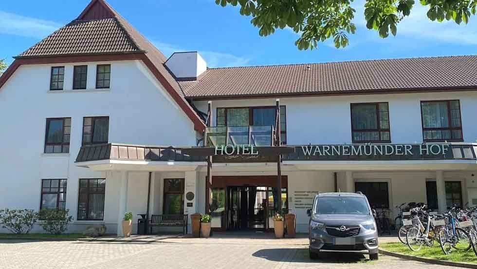 Eingangsbereich des Hotels Warnemünder Hof mit geparktem Auto und Fahrrädern davor.