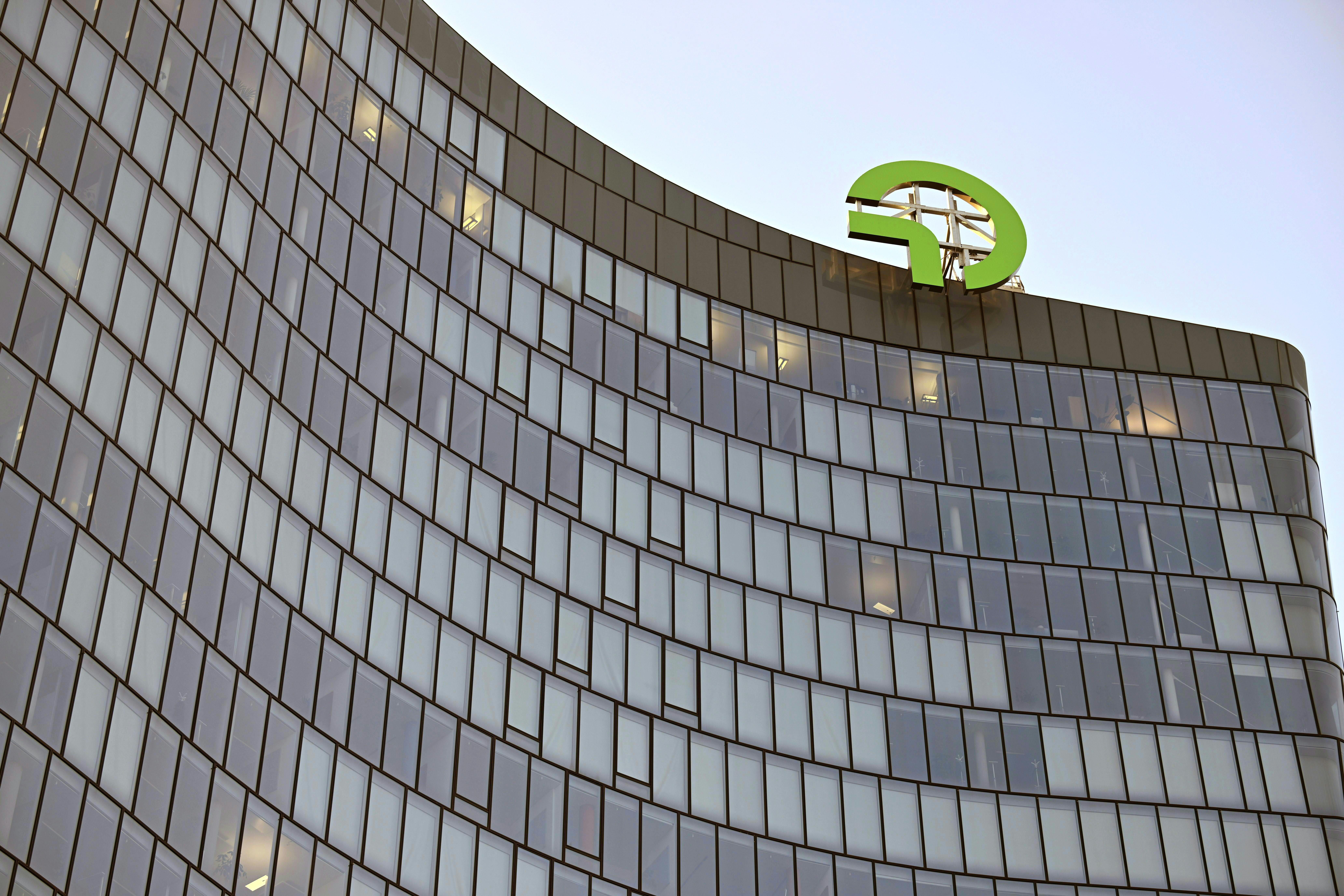 Geschwungenes Bürogebäude mit OMV-Logo auf dem Dach in Wien bei Tageslicht.
