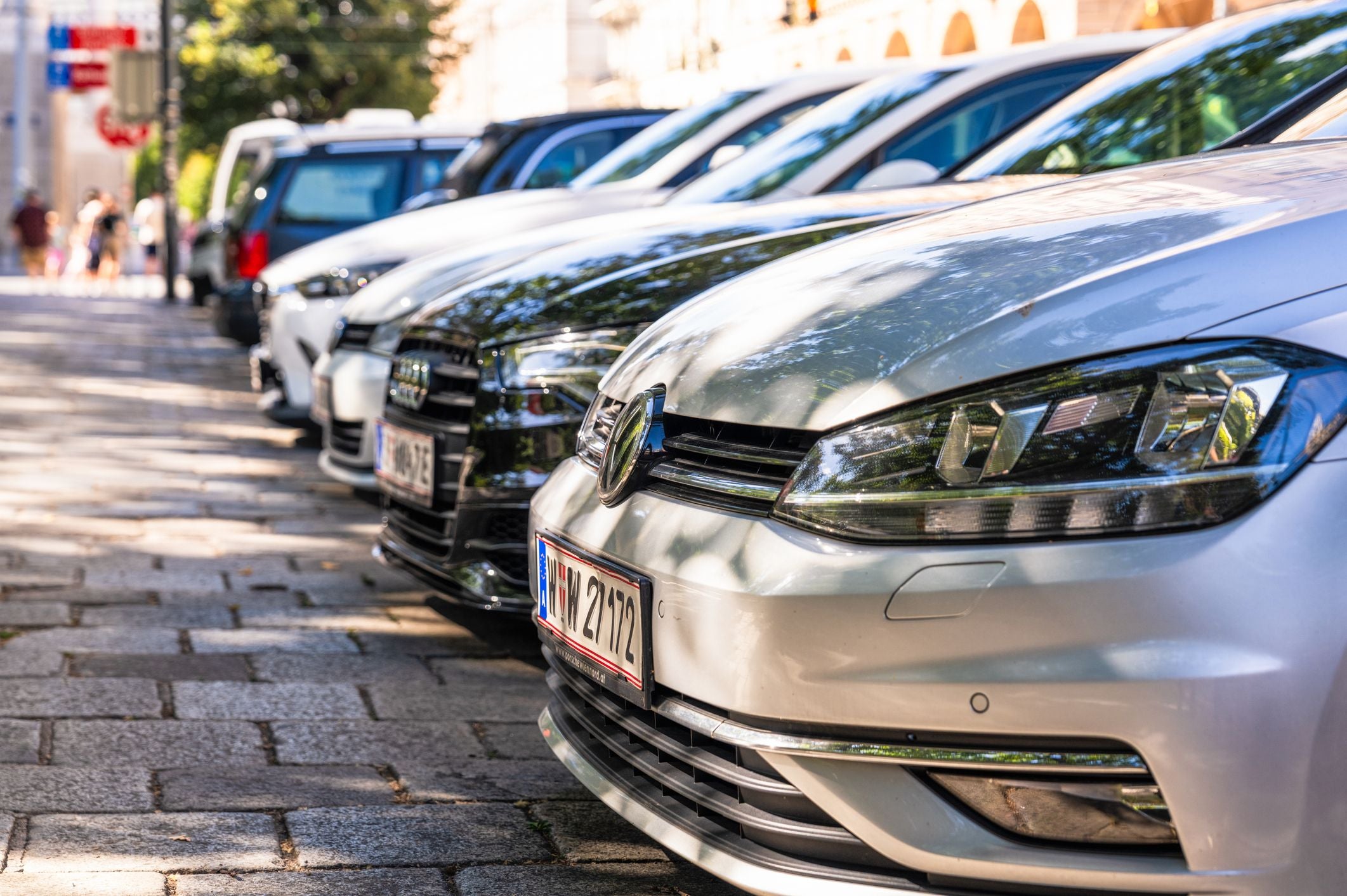 Mehrere moderne Autos sind in einer Reihe am Straßenrand im Zentrum von Wien geparkt.