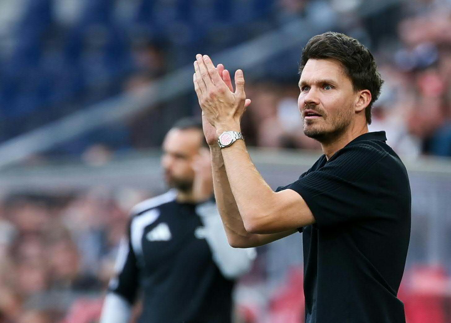 Salzburg-Trainer Danny Röhl blickt aufmerksam und klatscht mit den Händen vor der Trainerbank.