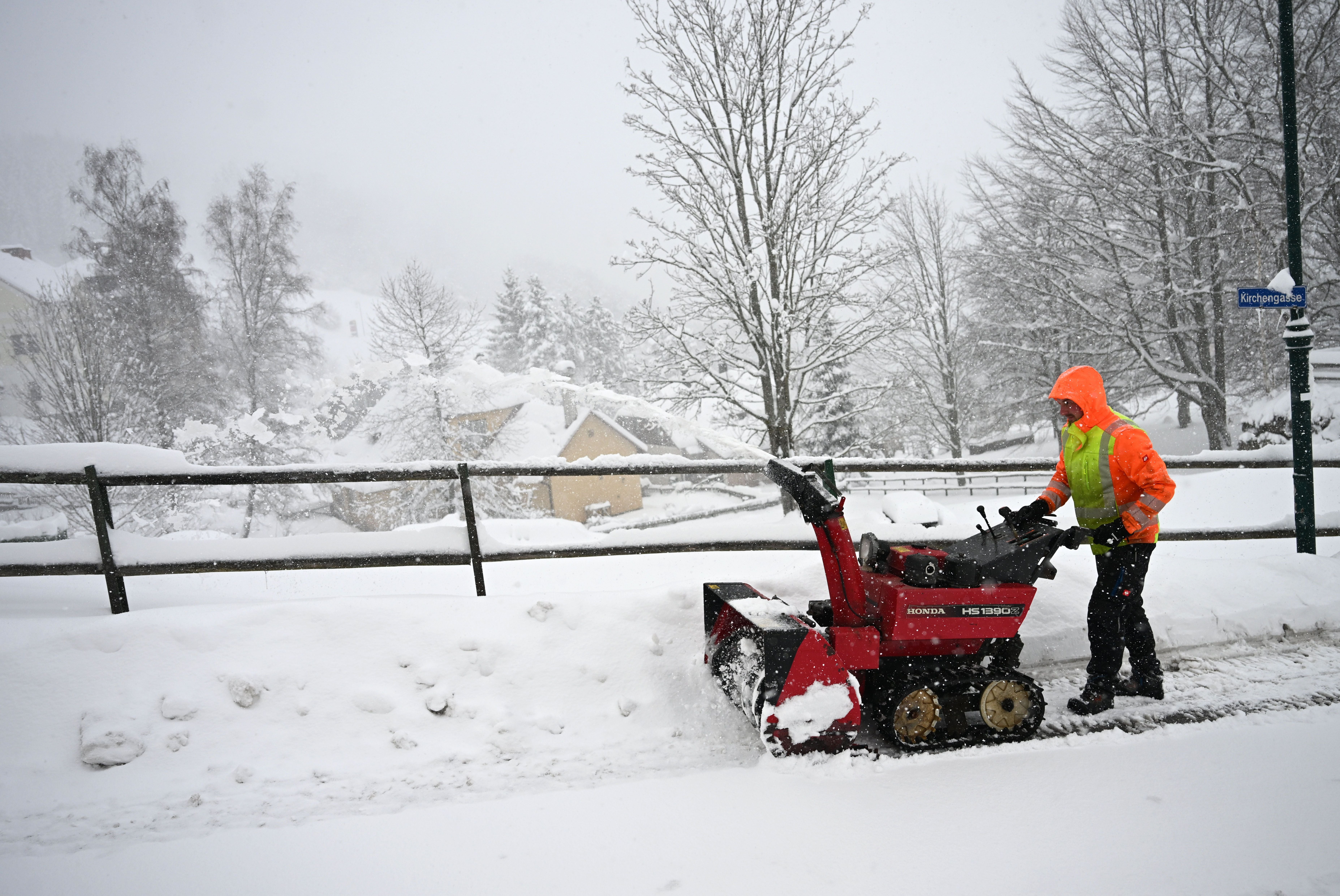 Ein Mann räumt mit einer Schneefräse eine verschneite Straße im Winter in Puchenstuben.